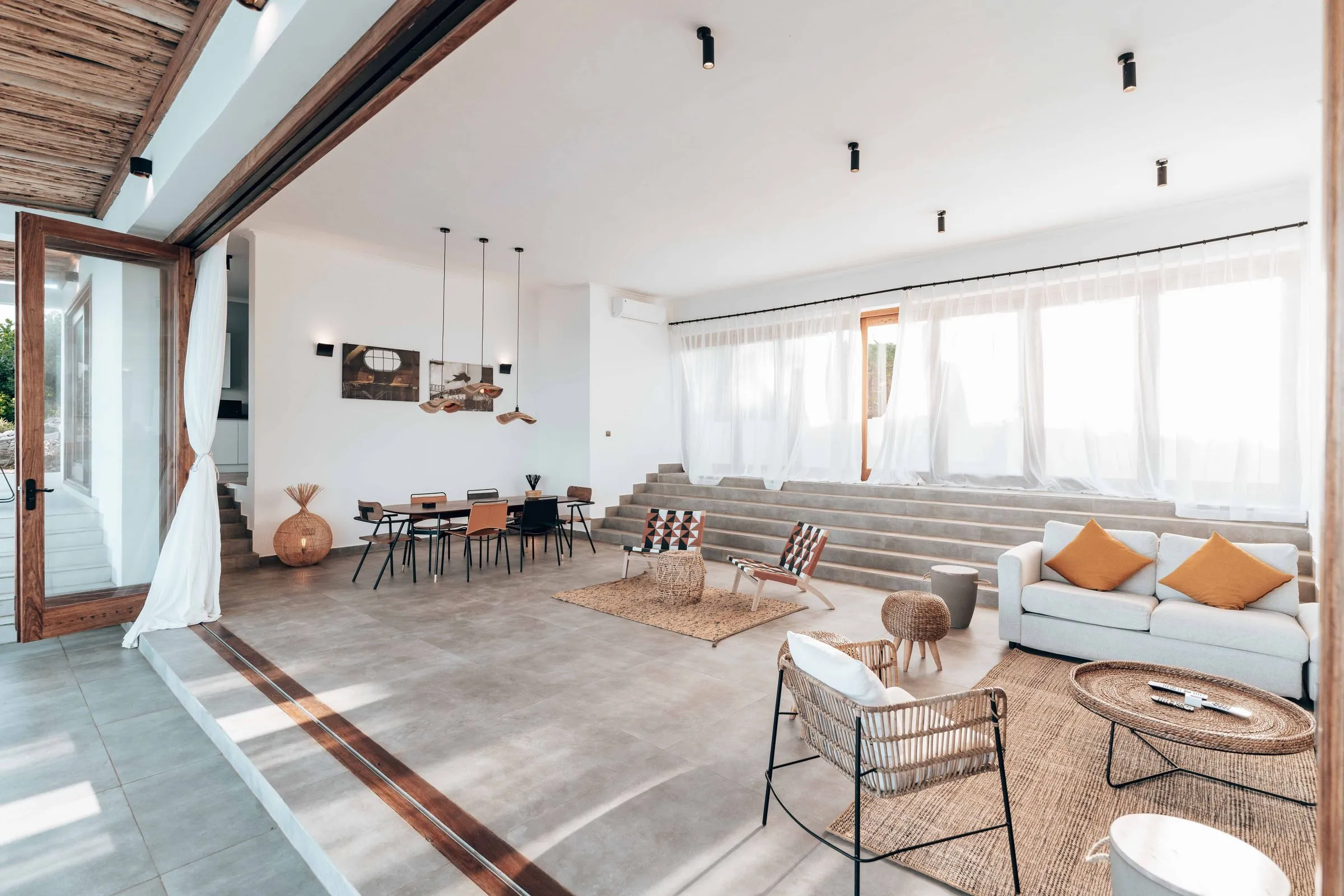 A wide open-plan living space with full-height glazing and a pale timber floor.