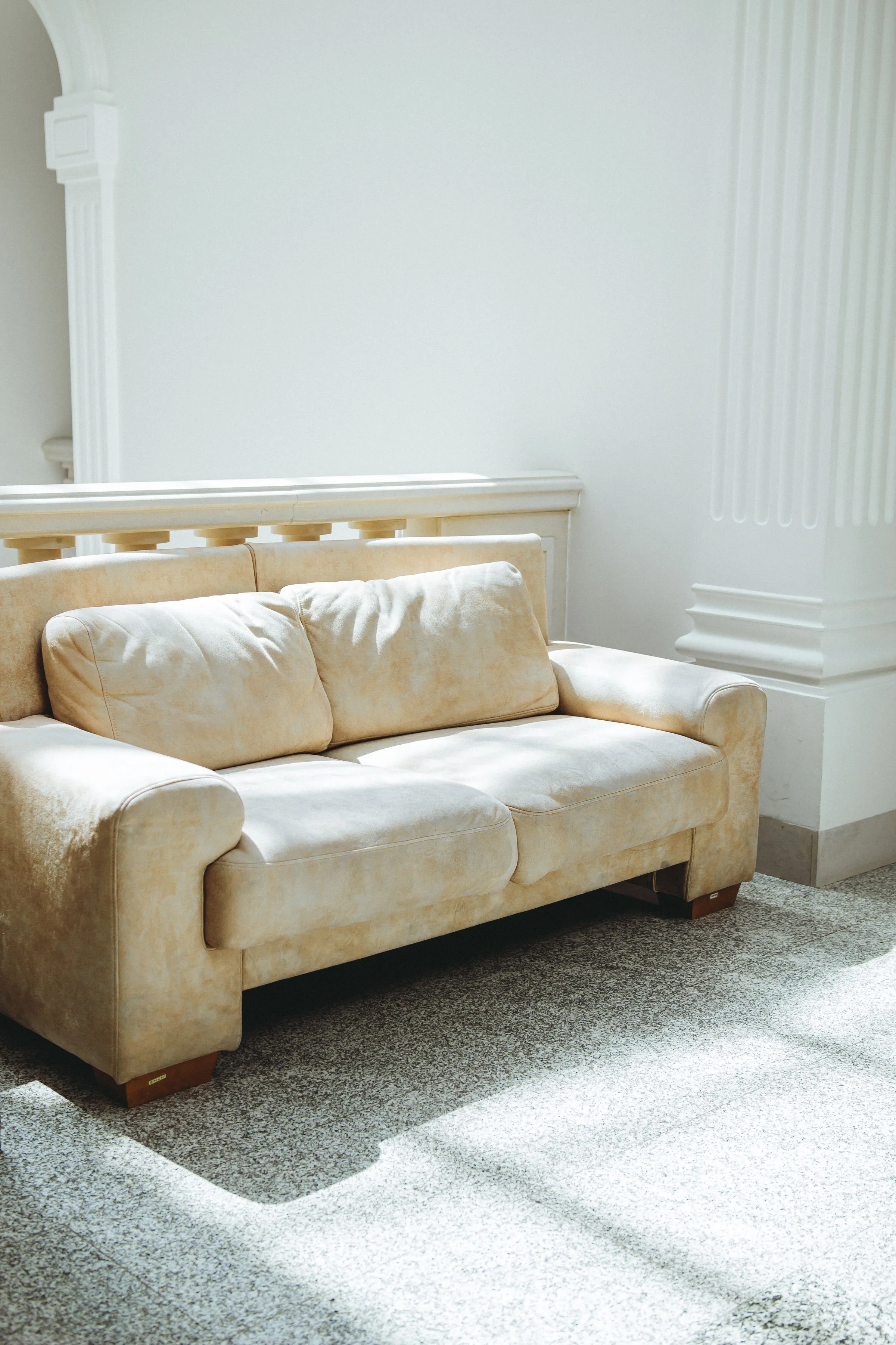 A cream sofa in a sunlit room with panelled walls and quiet classical mouldings.