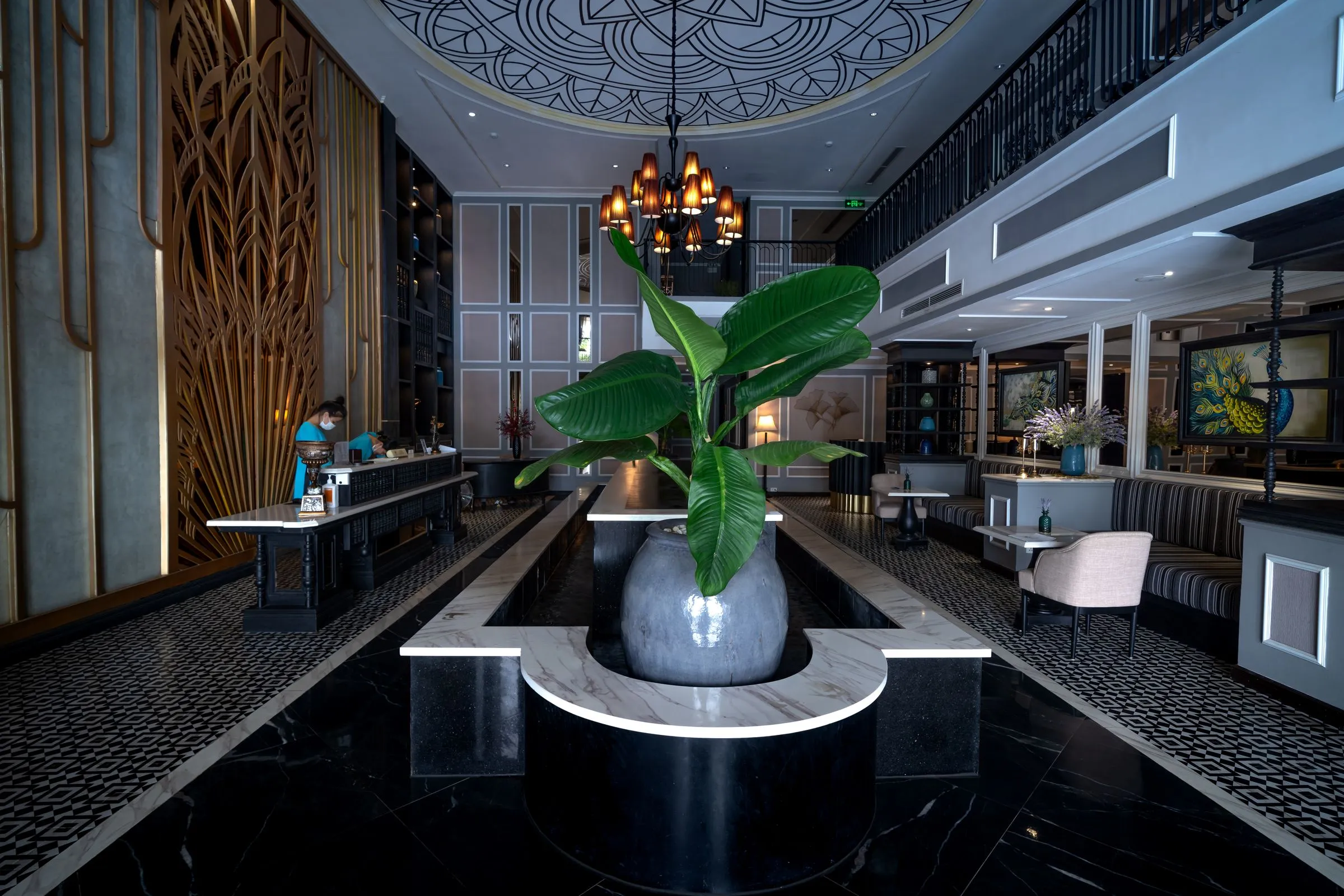 Lobby seating at Hotel Marana beneath a large chandelier, with planting at the centre.