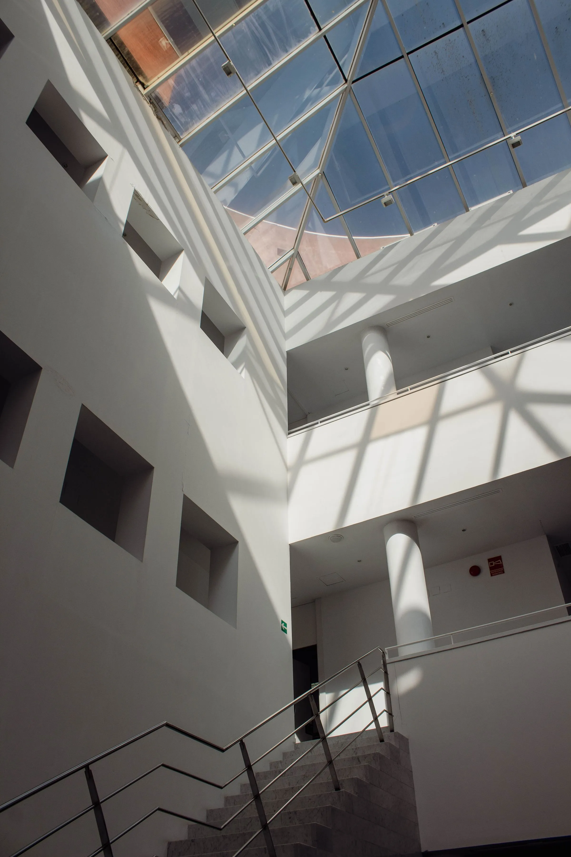A low-angle view of a glass roof over a pale minimal interior.