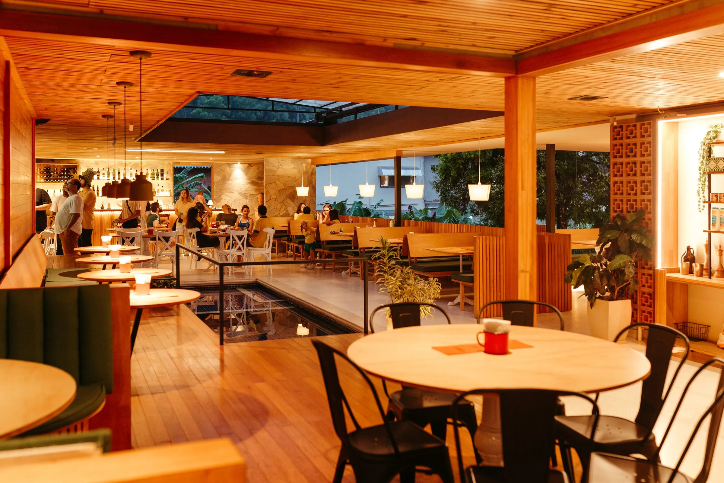 A restaurant interior with timber tables, banquette seating and warm lighting.