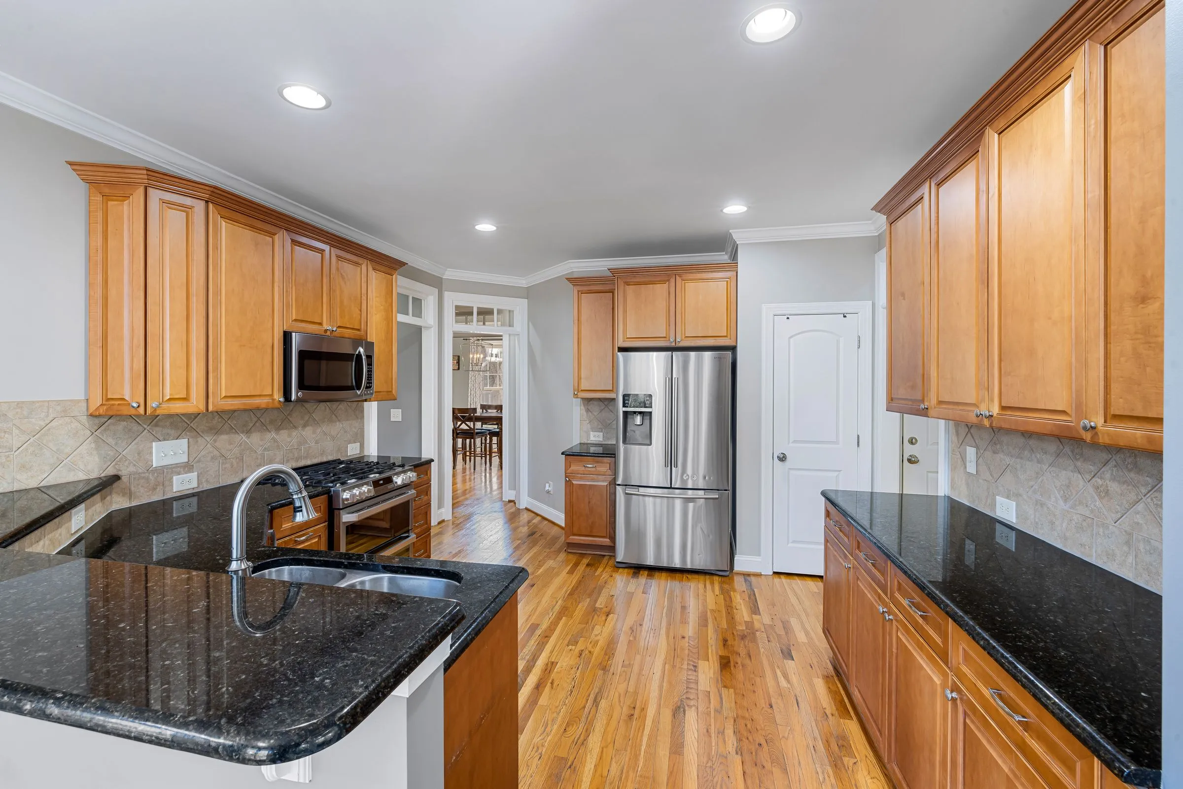 A kitchen with a large island, timber cabinets and stainless appliances.