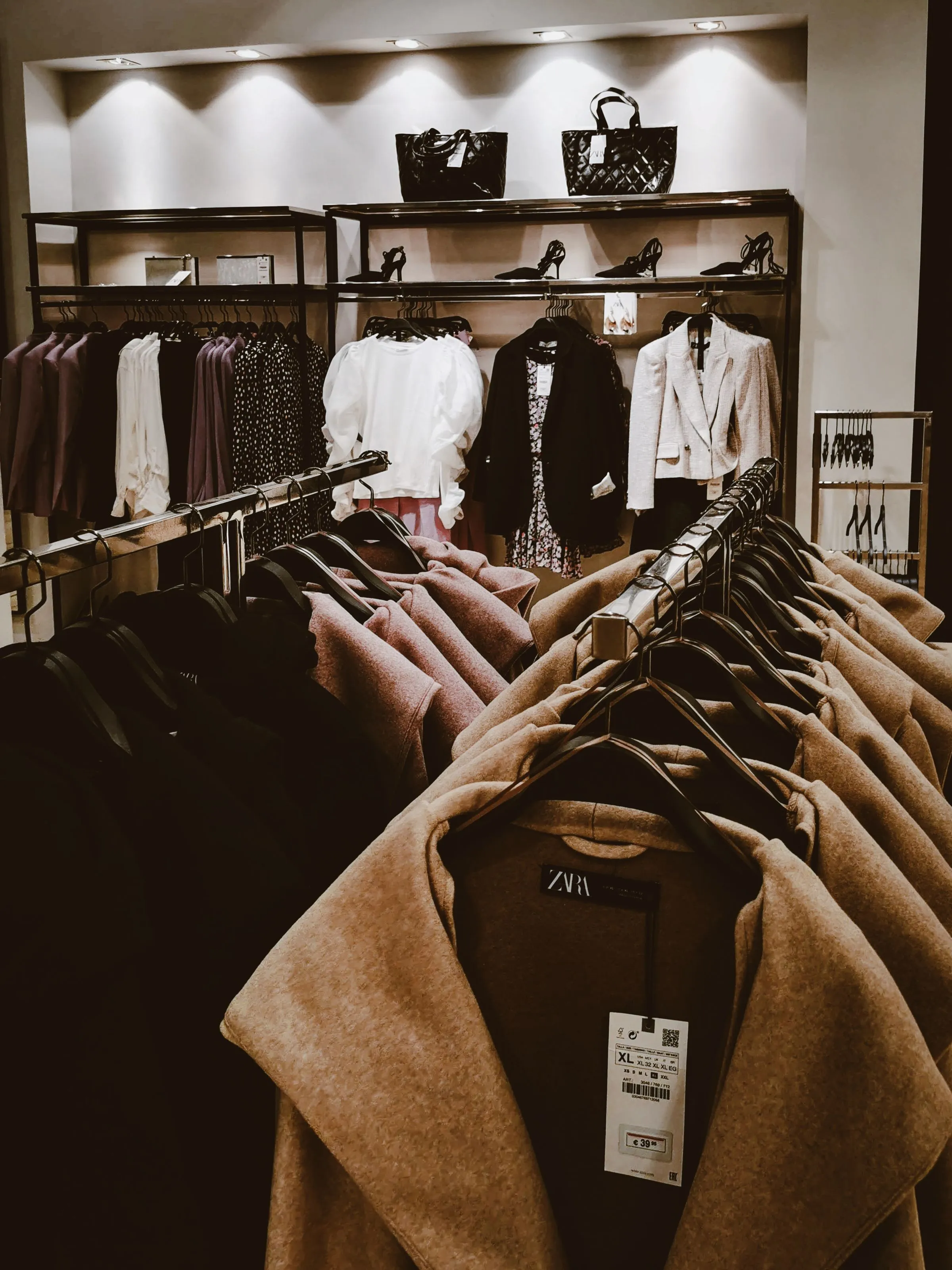 Anodised metal clothing rails holding garments at Vault & Vine.