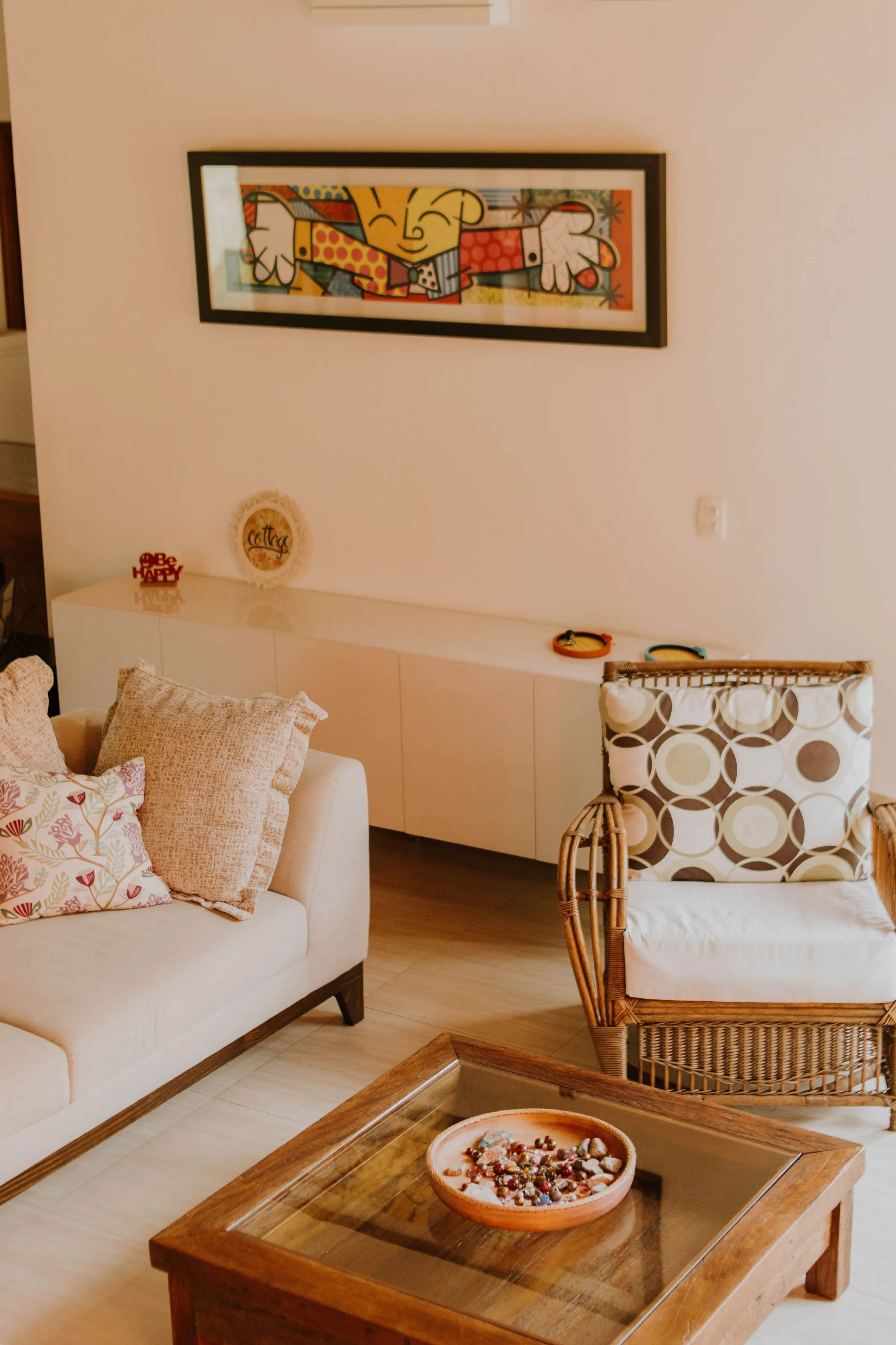A warm living room with modern art, a rattan chair and a low sofa.