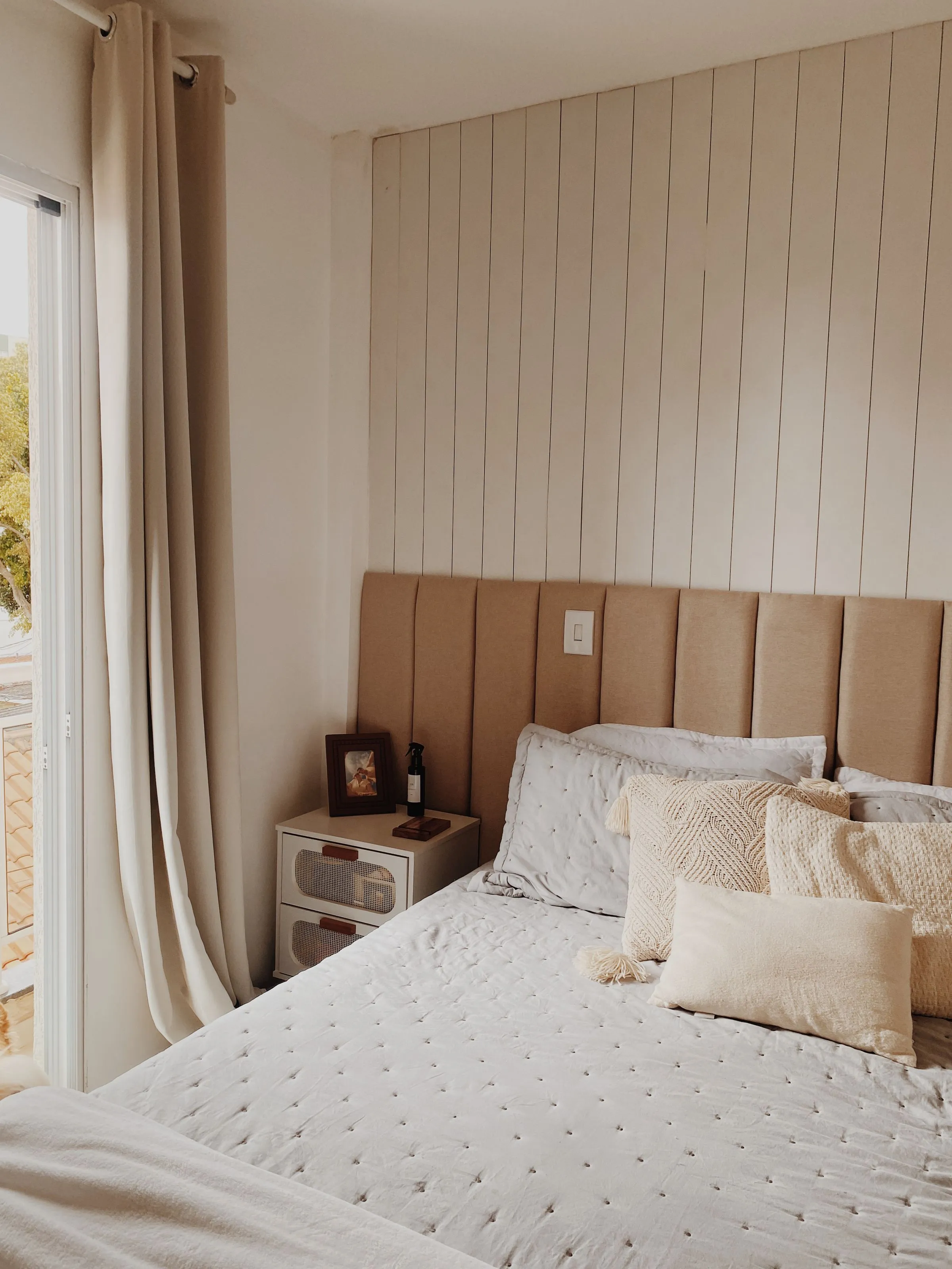 A beige-toned bedroom with panelled walls and simple contemporary furniture.
