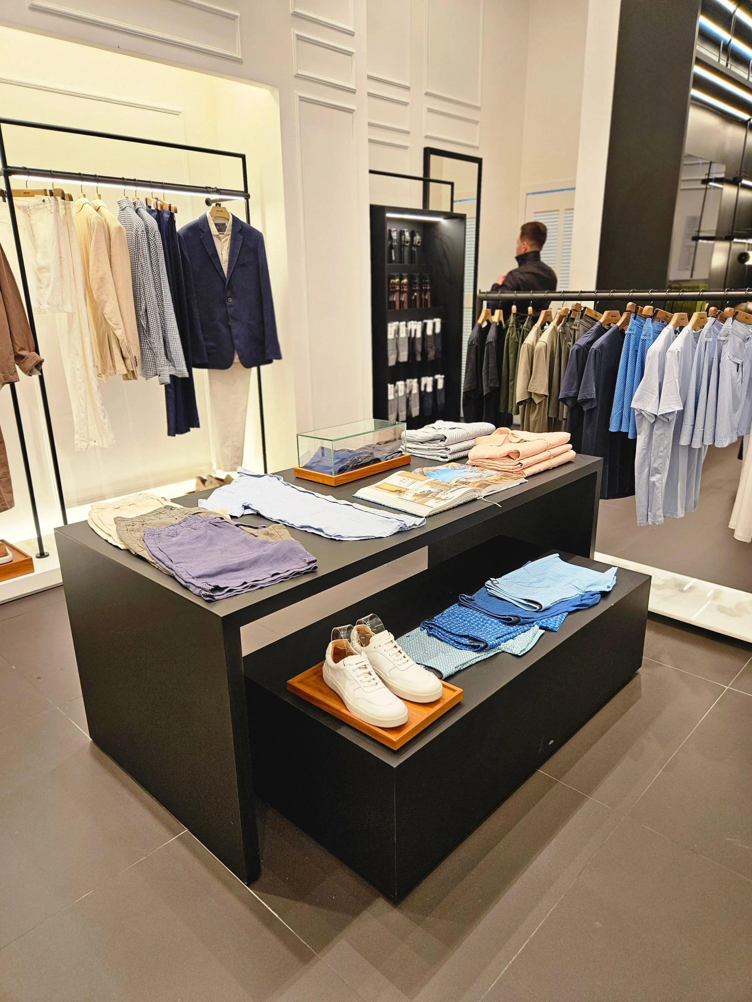 Tailored menswear on rails at Vault & Vine under directional track lighting.