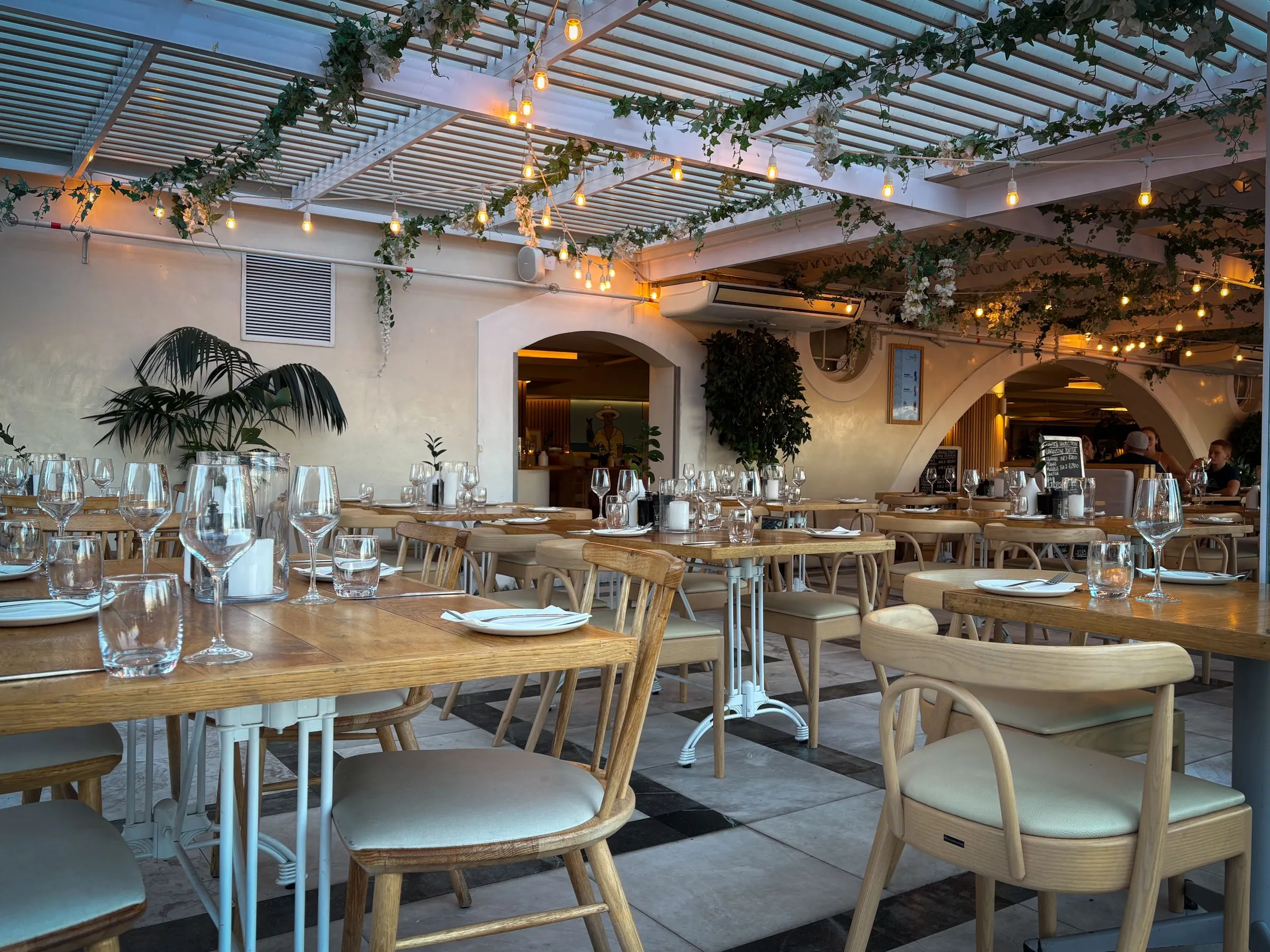 The Salt Room dining hall with timber furniture, warm lighting and planting along the walls.