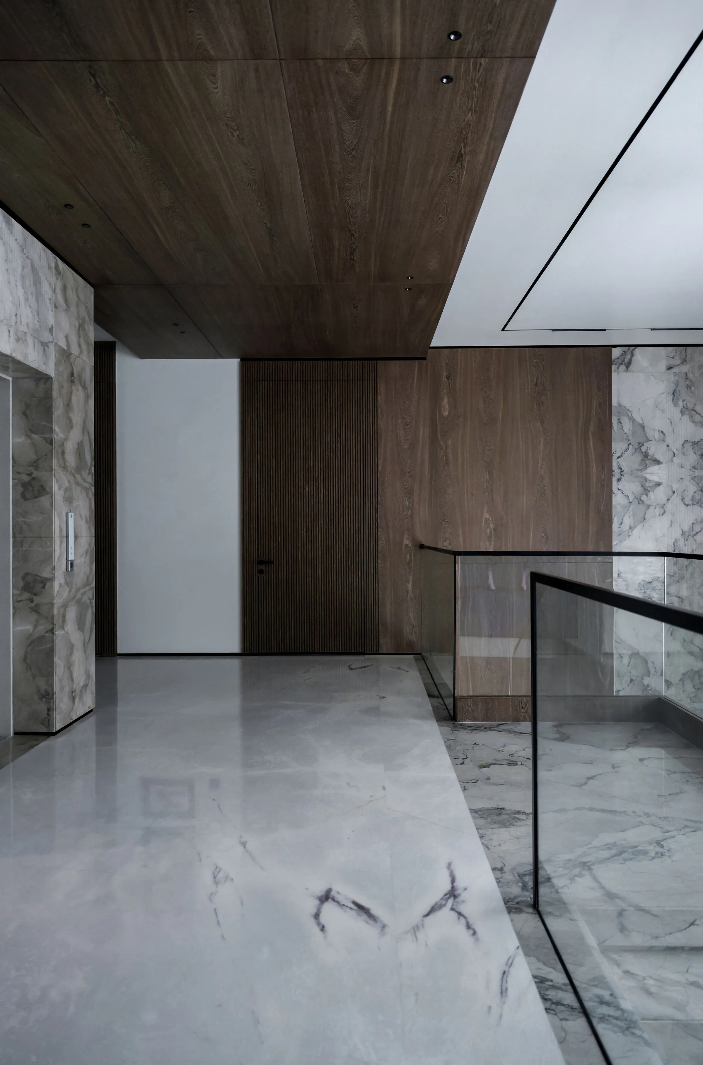 Stair hall at Casa Terra lined in pale marble and wood panelling.