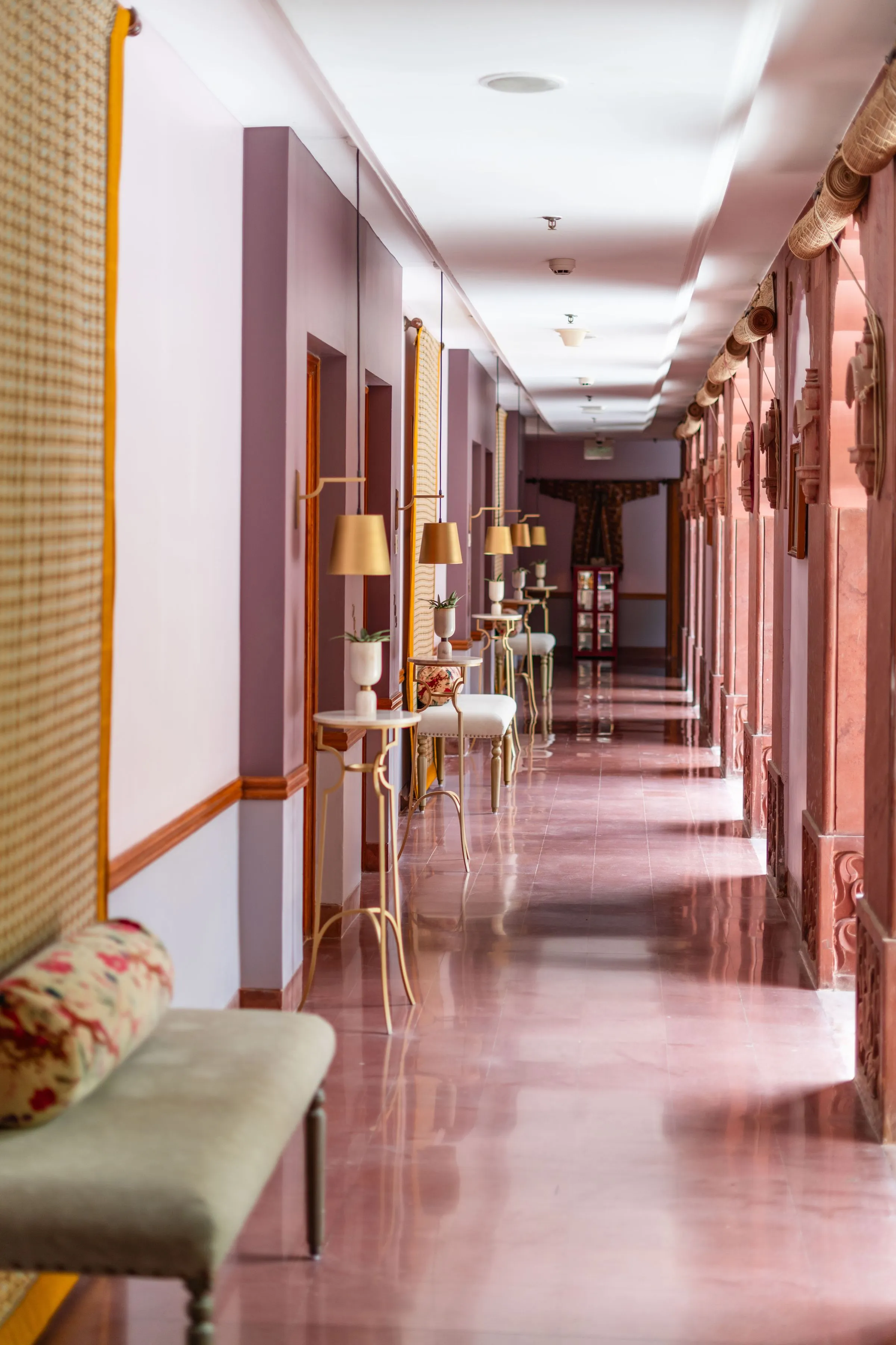A long corridor in a heritage building with arched openings and patterned floors.