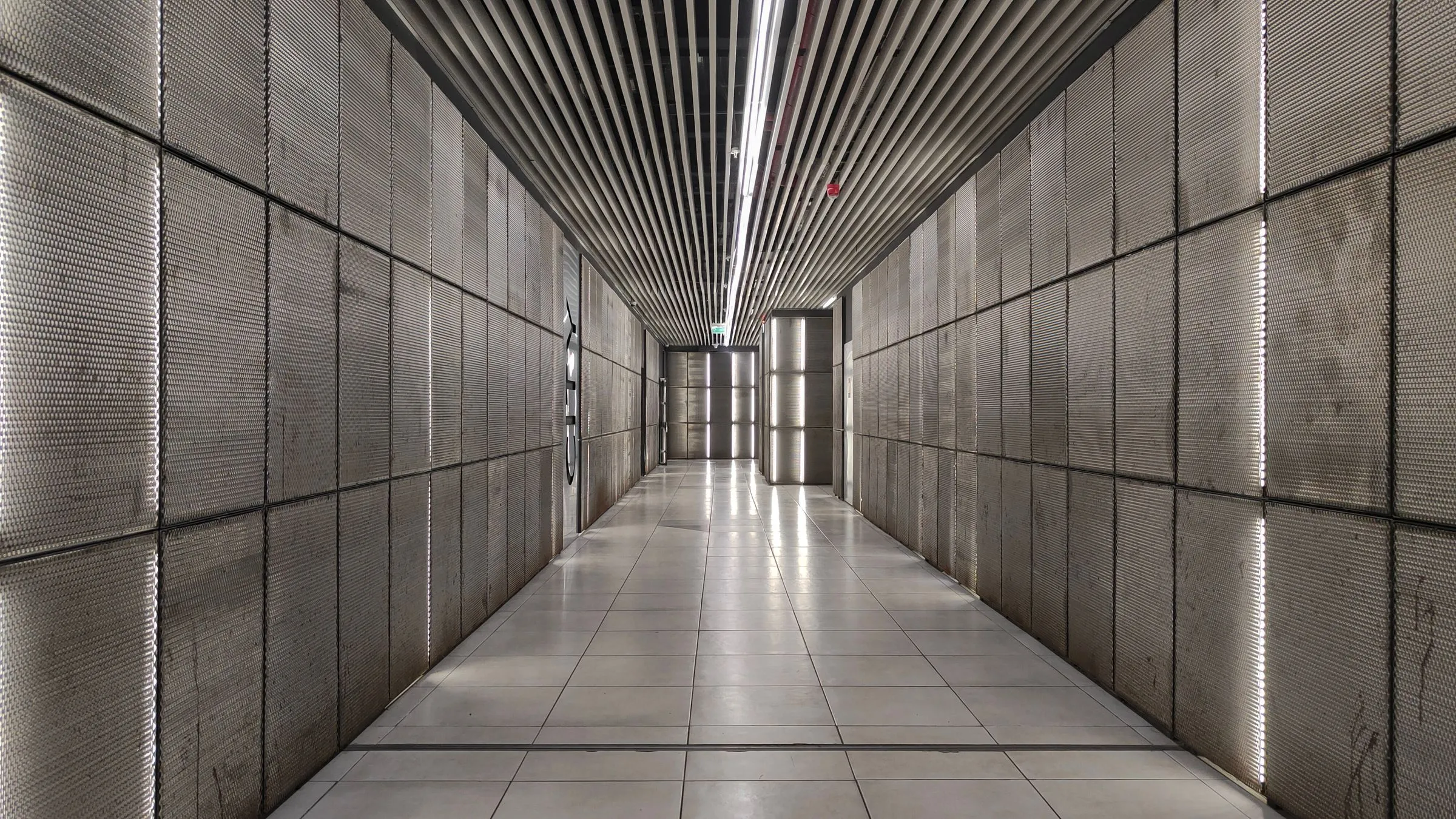 A minimal corridor with textured walls receding toward a lit opening.