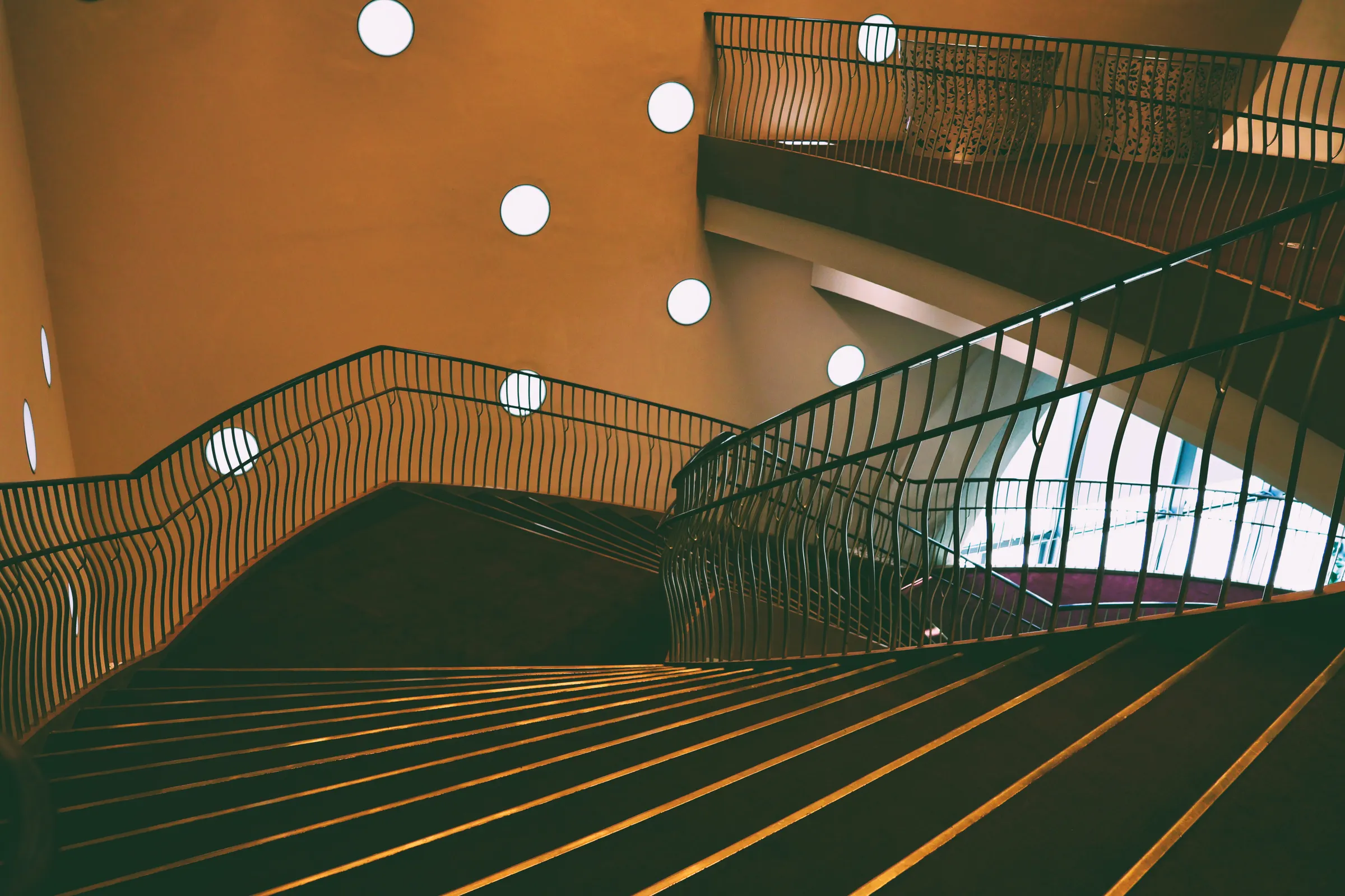 A sweeping curved staircase rising through a top-lit space.