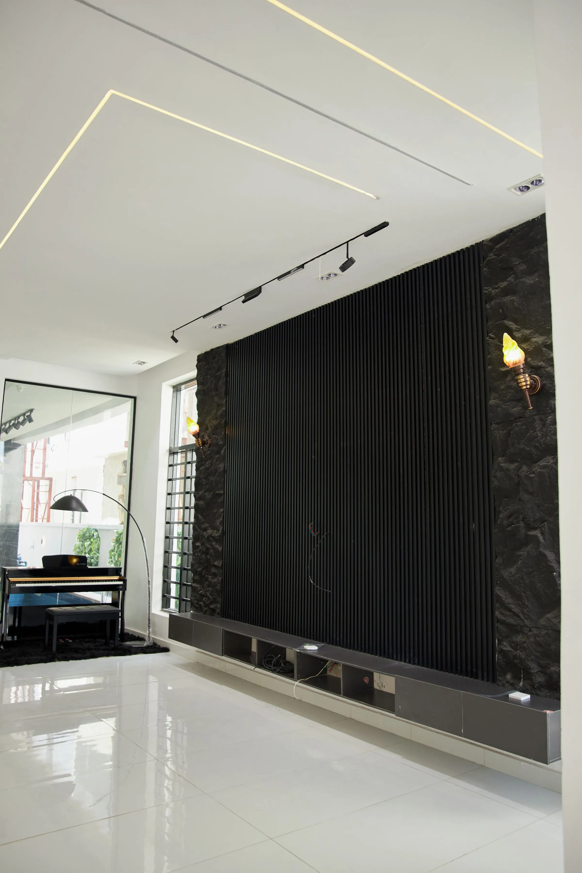 A contemporary room with a black accent wall, a piano corner and minimal lighting.