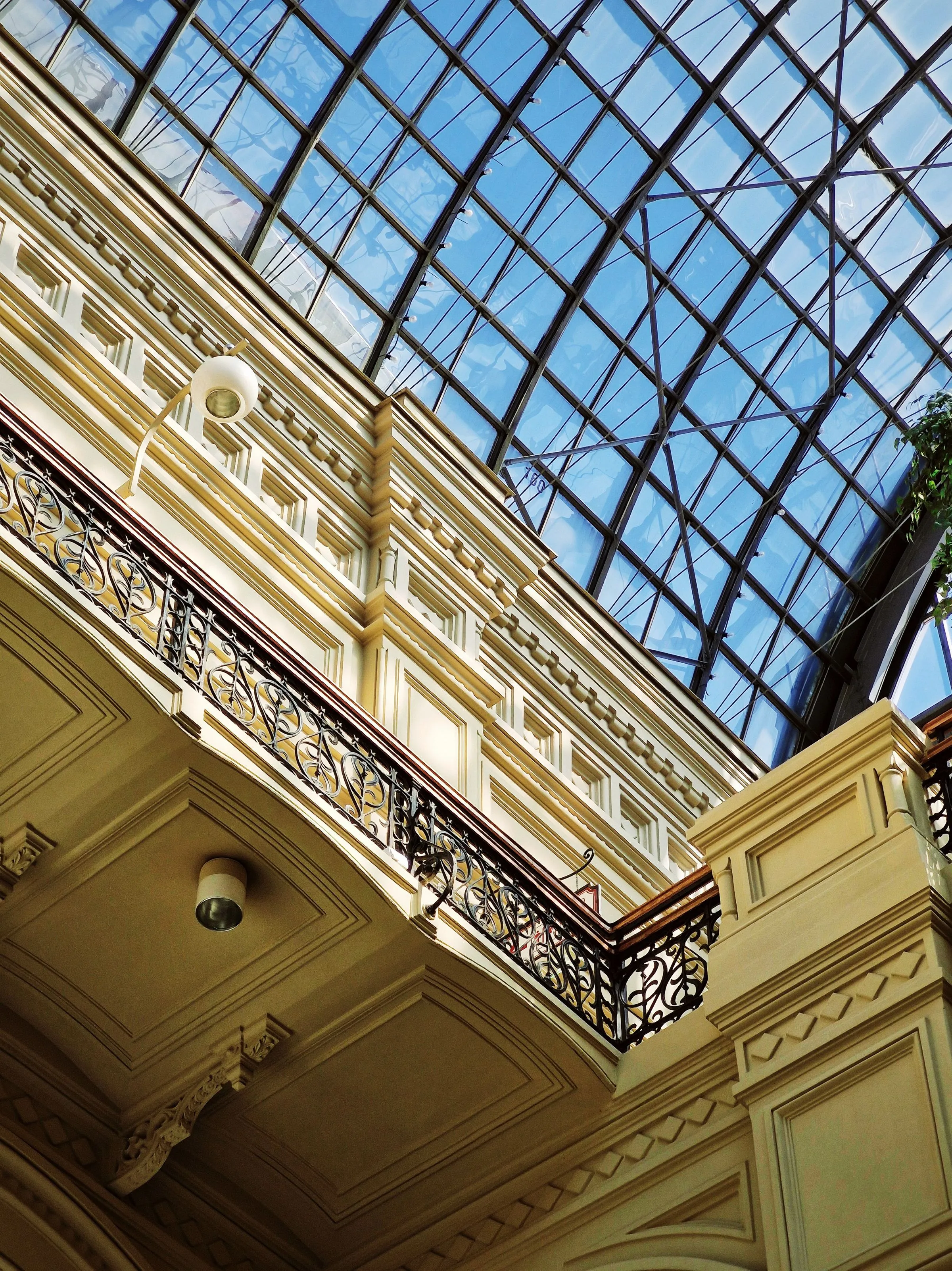 Looking up through a glazed atrium roof at the railings of the floors above.