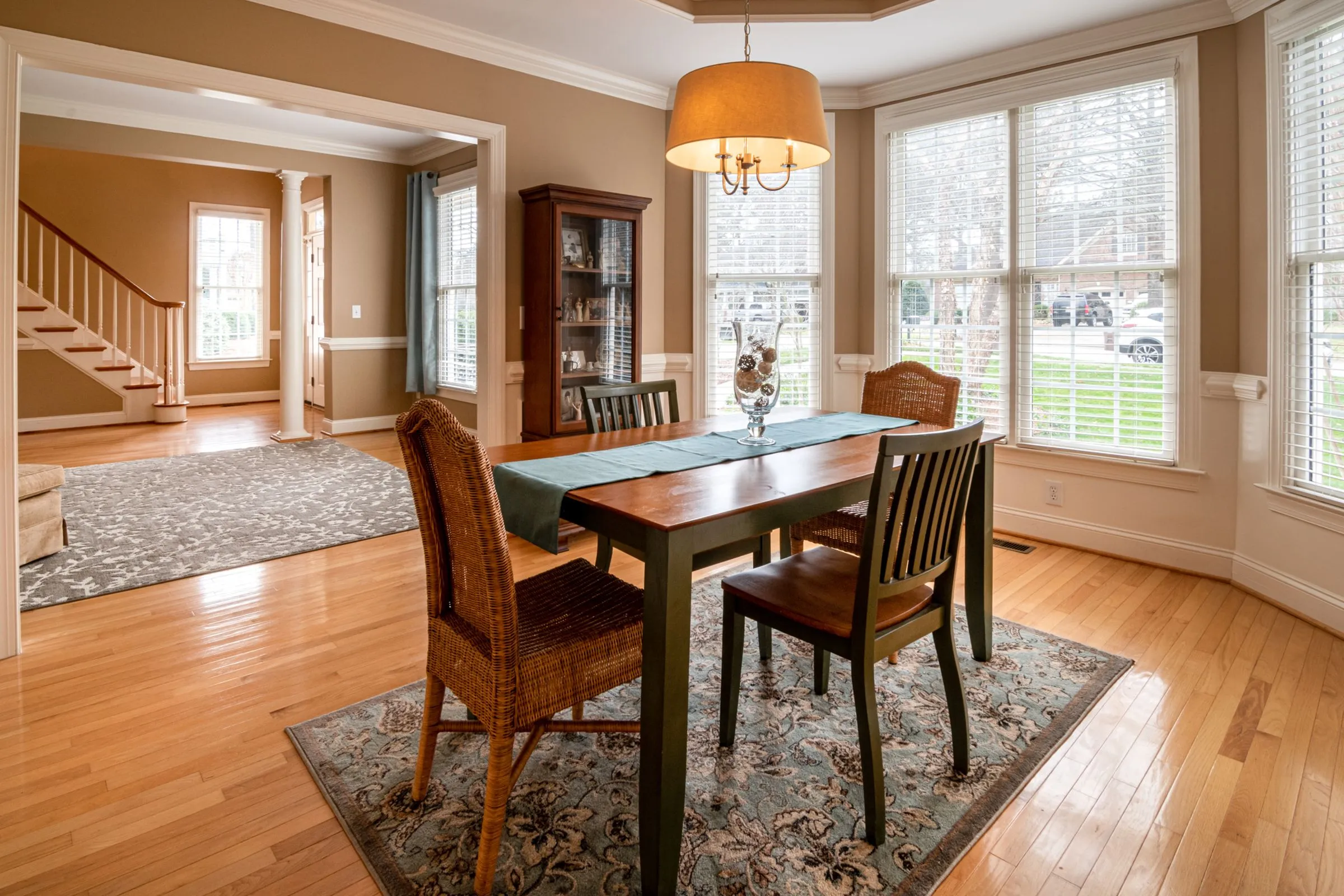 A sunlit dining room with a timber table and woven chairs.