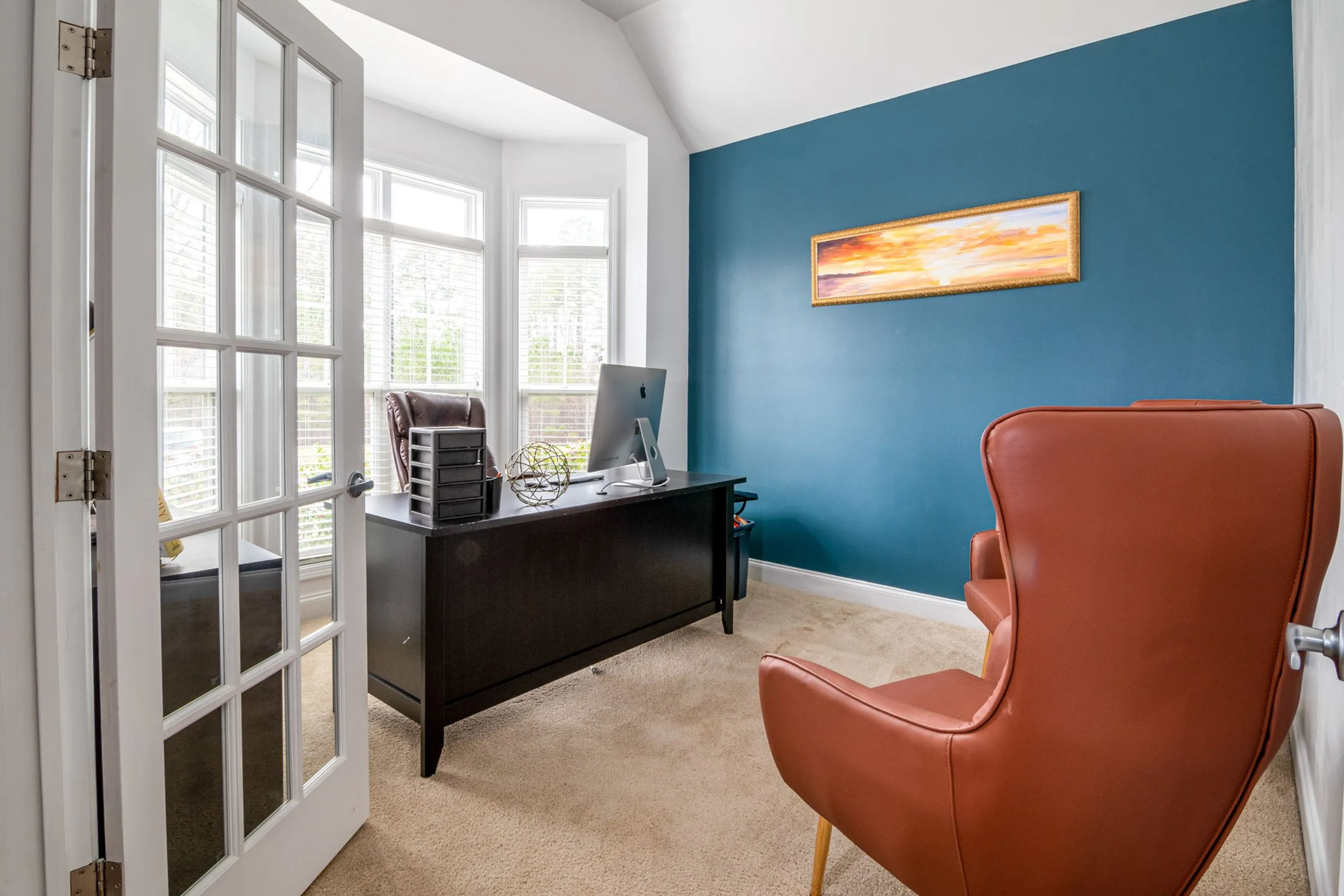 A calm consulting room with a desk, a leather chair and natural light.