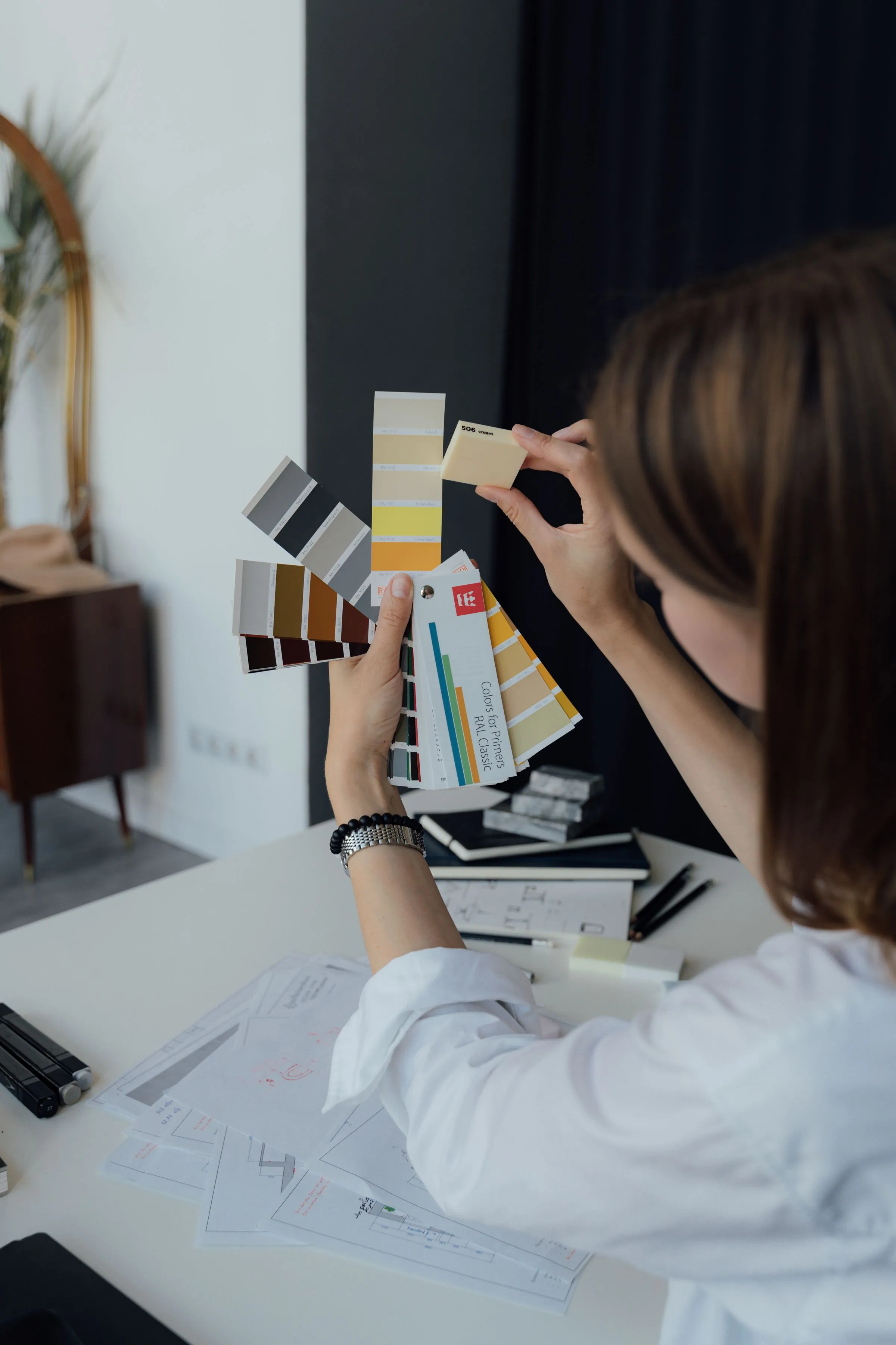 An interior designer comparing colour and finish sample swatches at a desk.