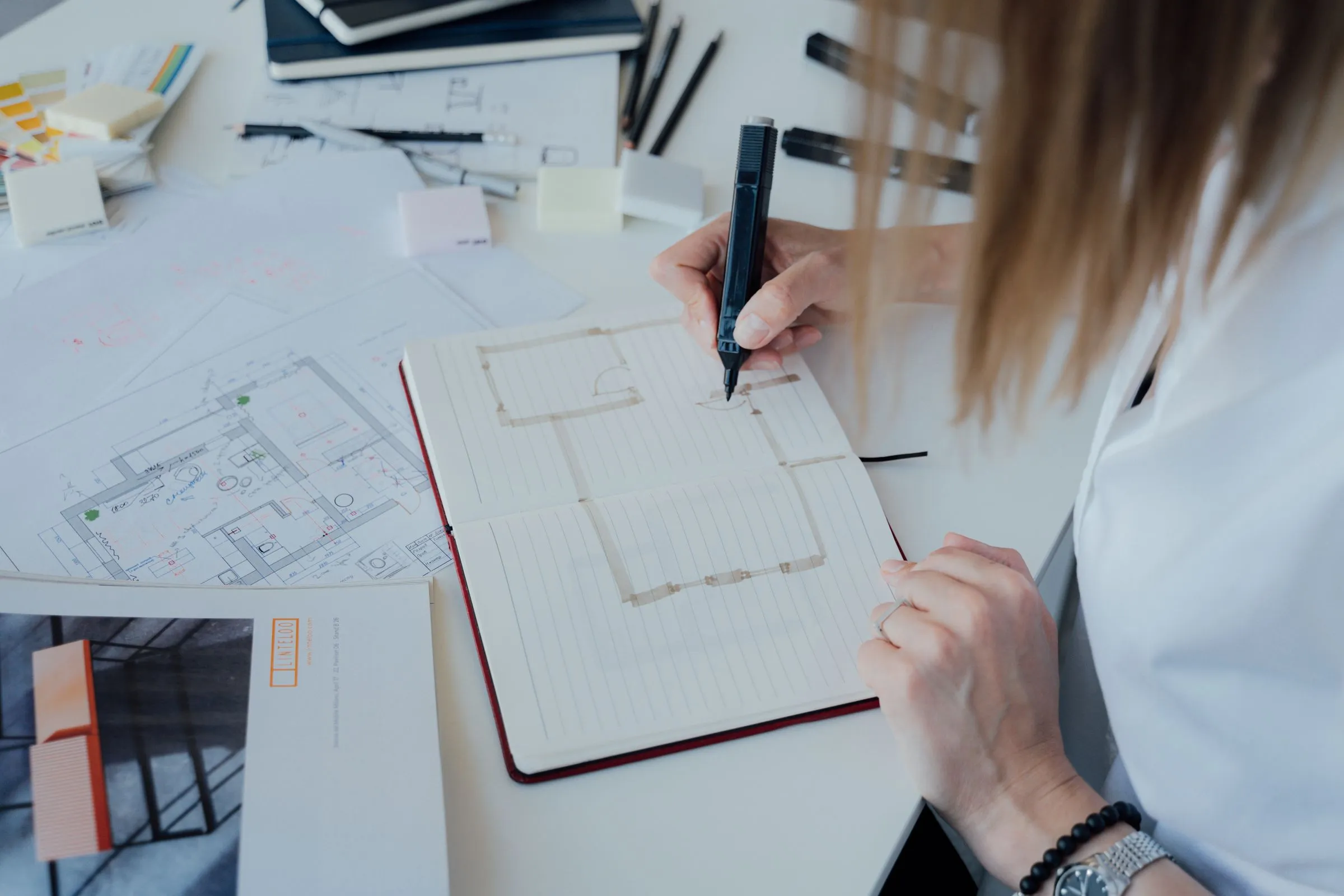 An architect sketching floor plans at an organised desk.