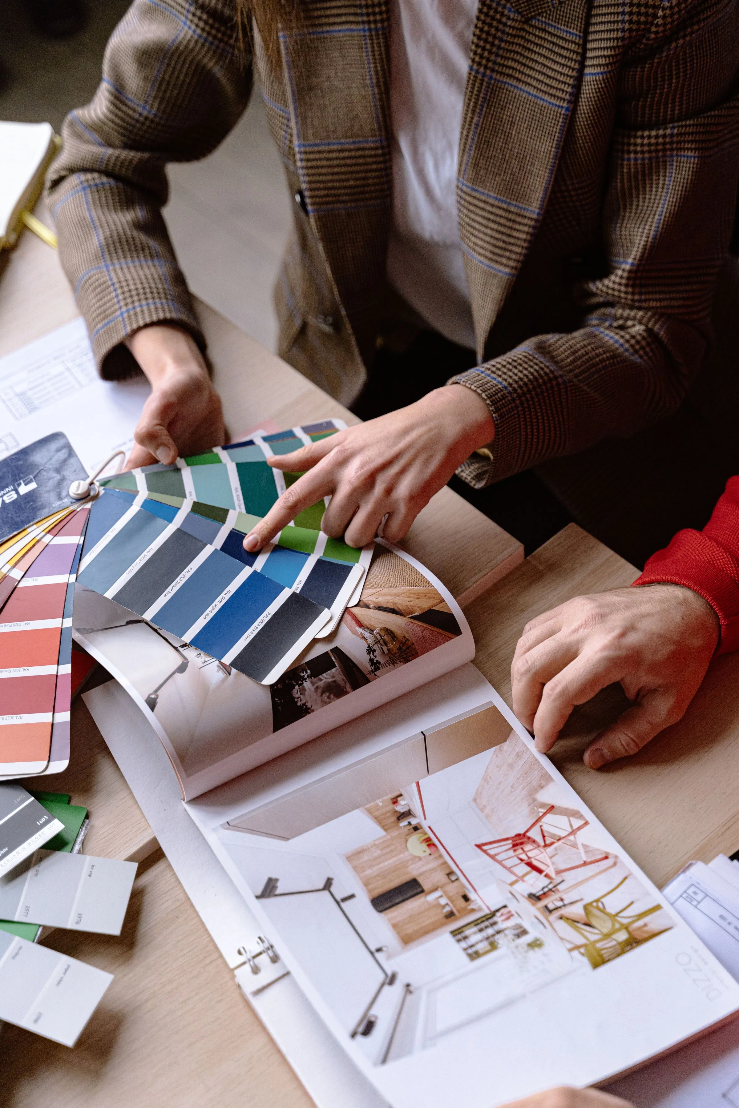 Two designers at a table comparing colour swatches and material samples.