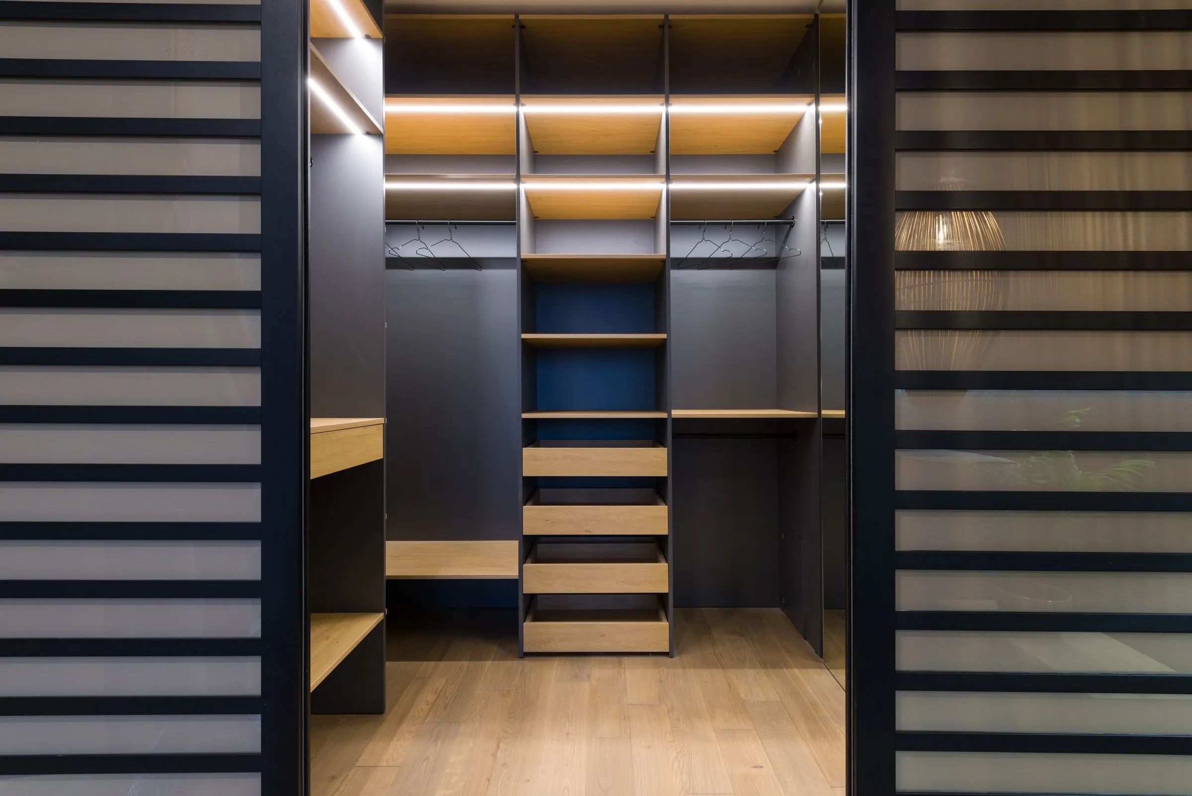 Walk-in wardrobe at Casa Terra with oiled timber shelving and concealed lighting.