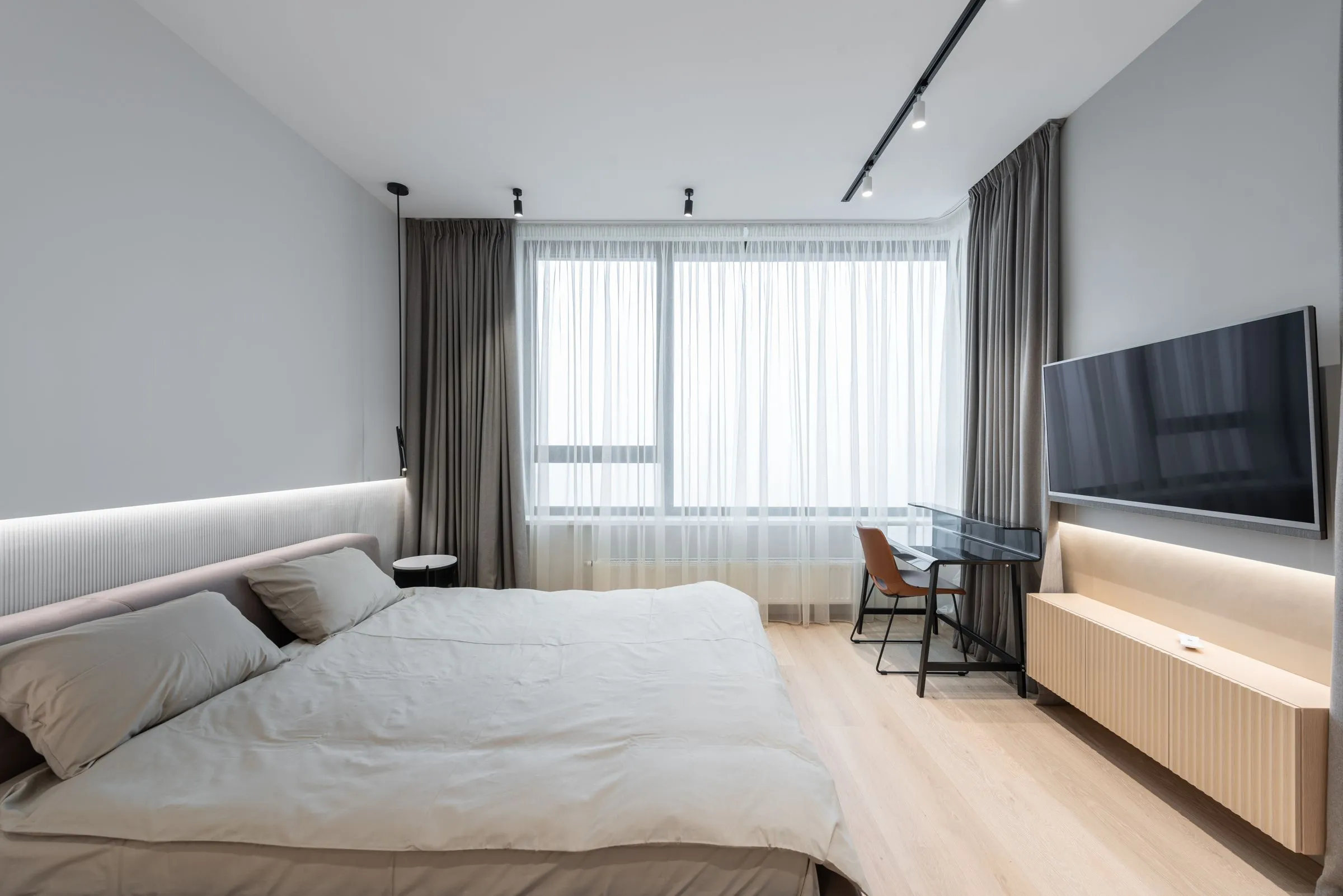 Guest room at Hotel Marana with a low bed, side table and curtains drawn back from the window.