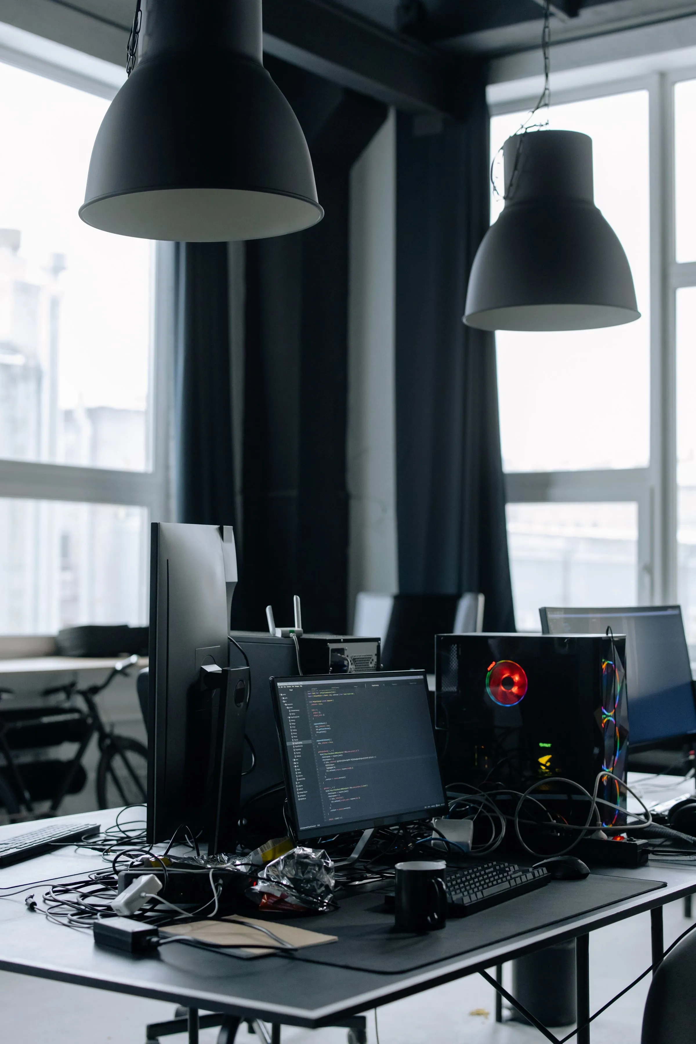 A working desk with monitors and equipment in a bright office.