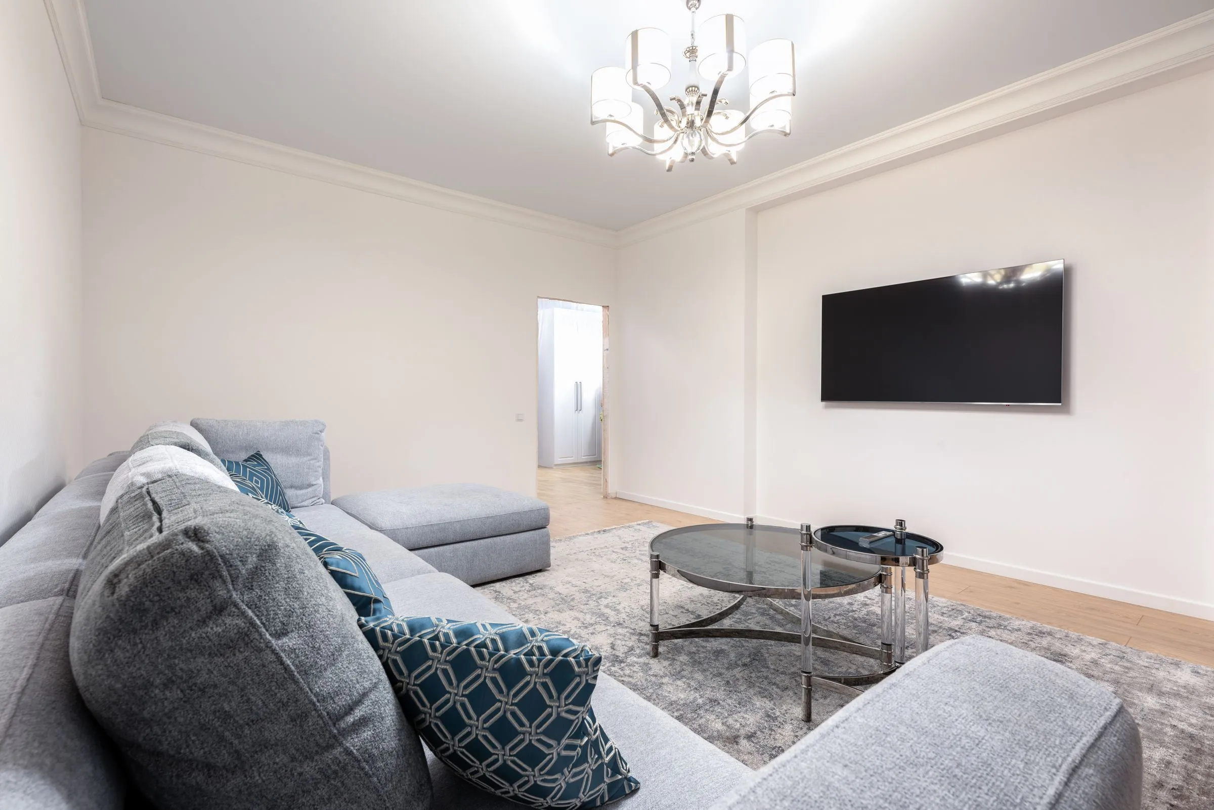 A room with a low couch, a dark screen and a large hanging light fitting.