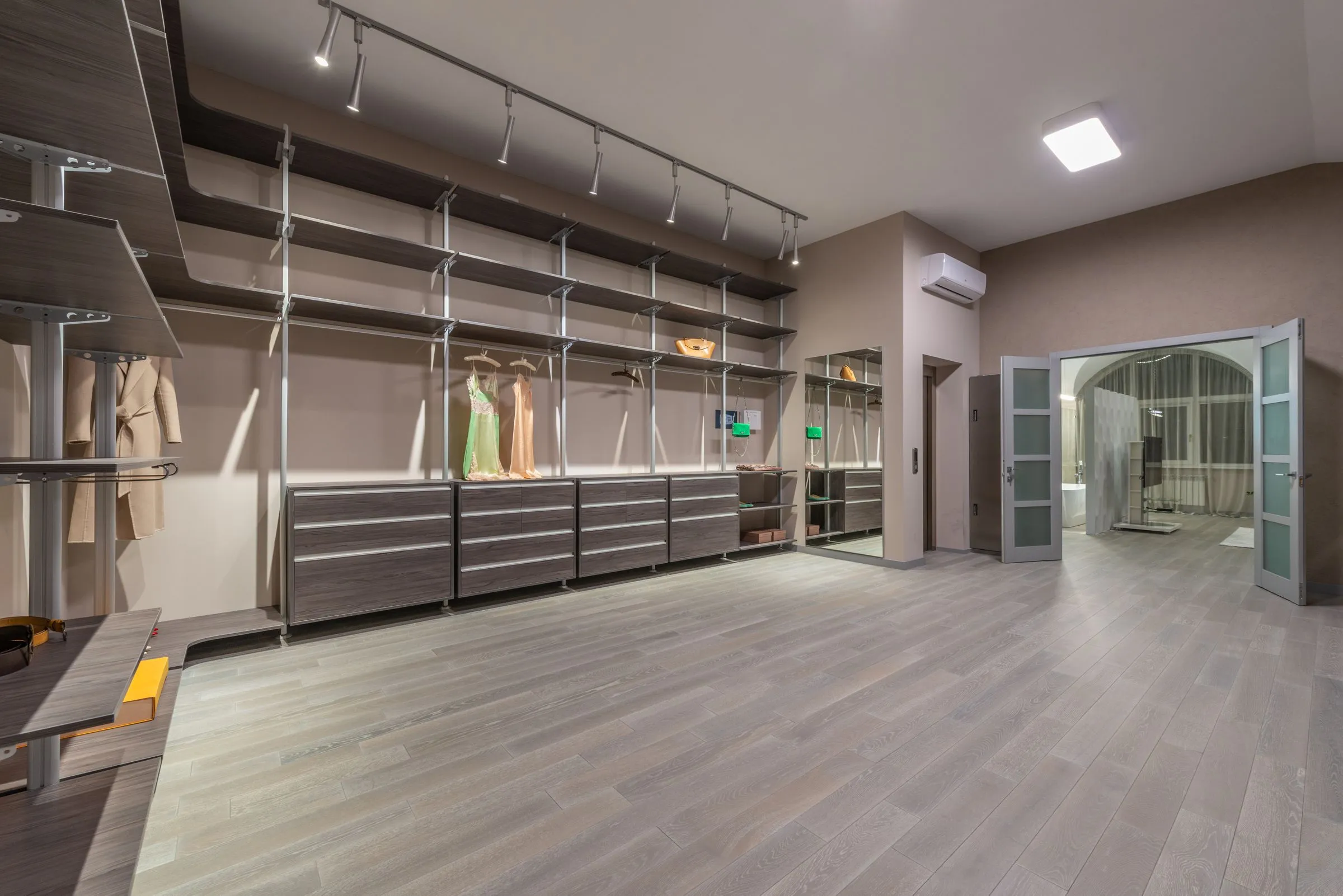 Garments and a coat hanging in a fitted timber wardrobe with open shelving.