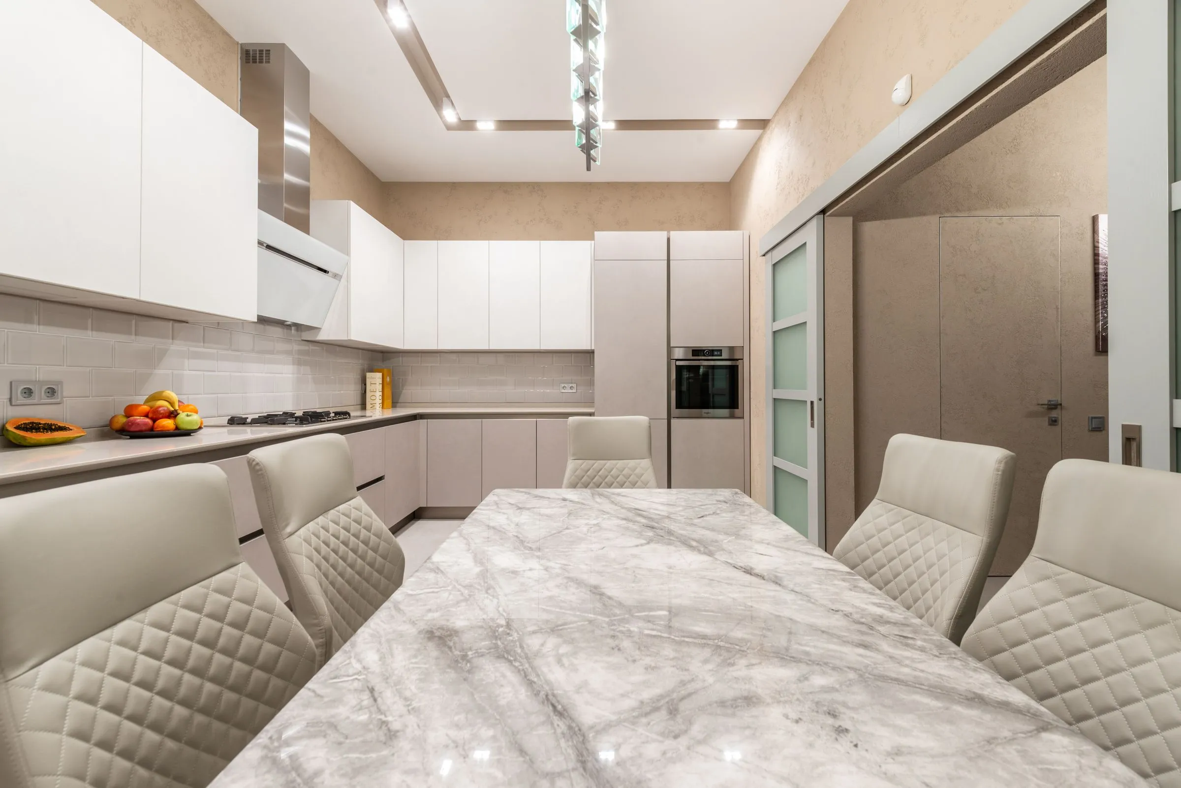 Serein kitchen in beige and white, with minimal cabinet fronts and a stone-topped table.