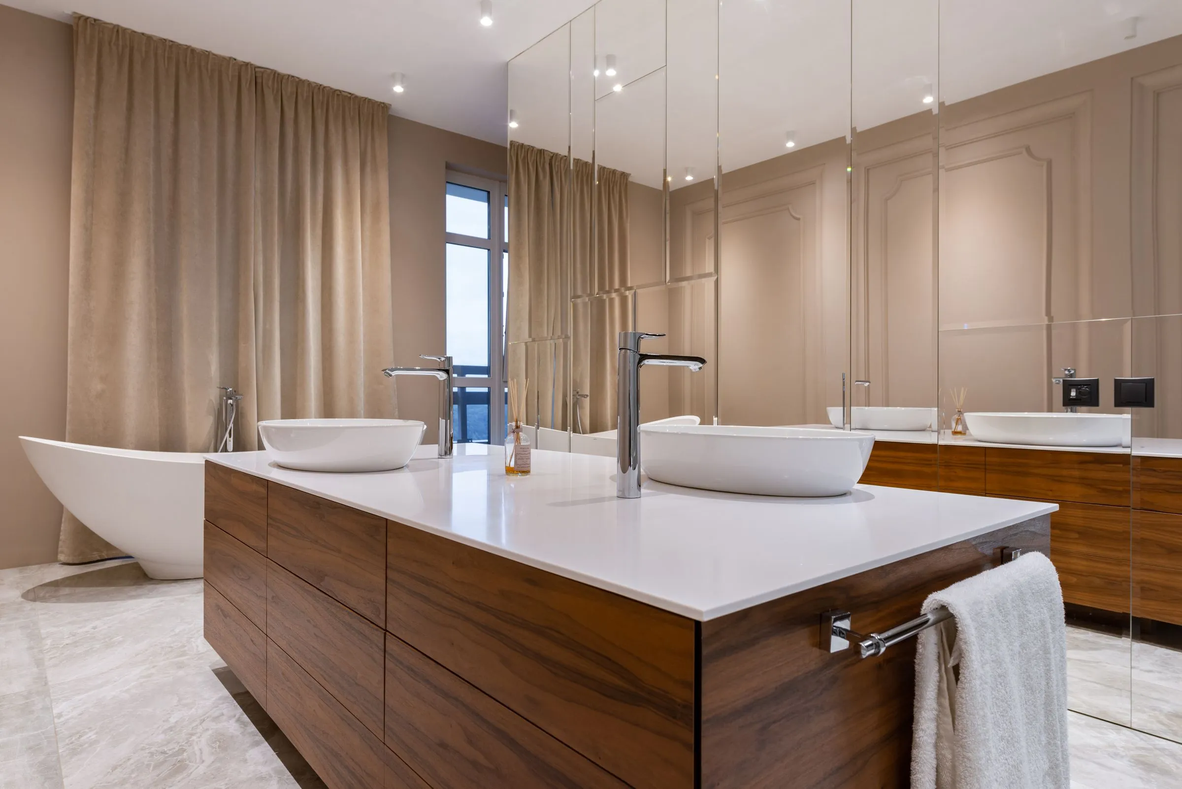 Compact bathroom at Kestrel House with a white basin, bath and mirrored cabinet.