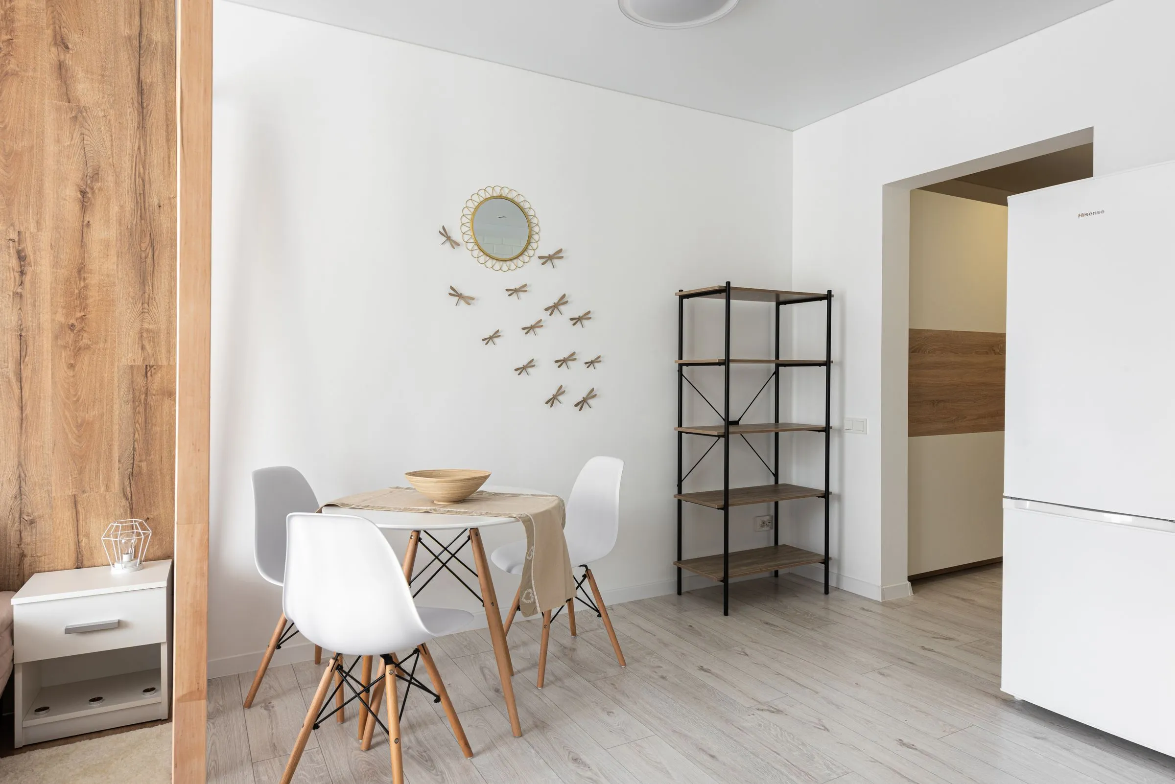 A dining room with a mirrored wall, a timber table and decorative wall detail.