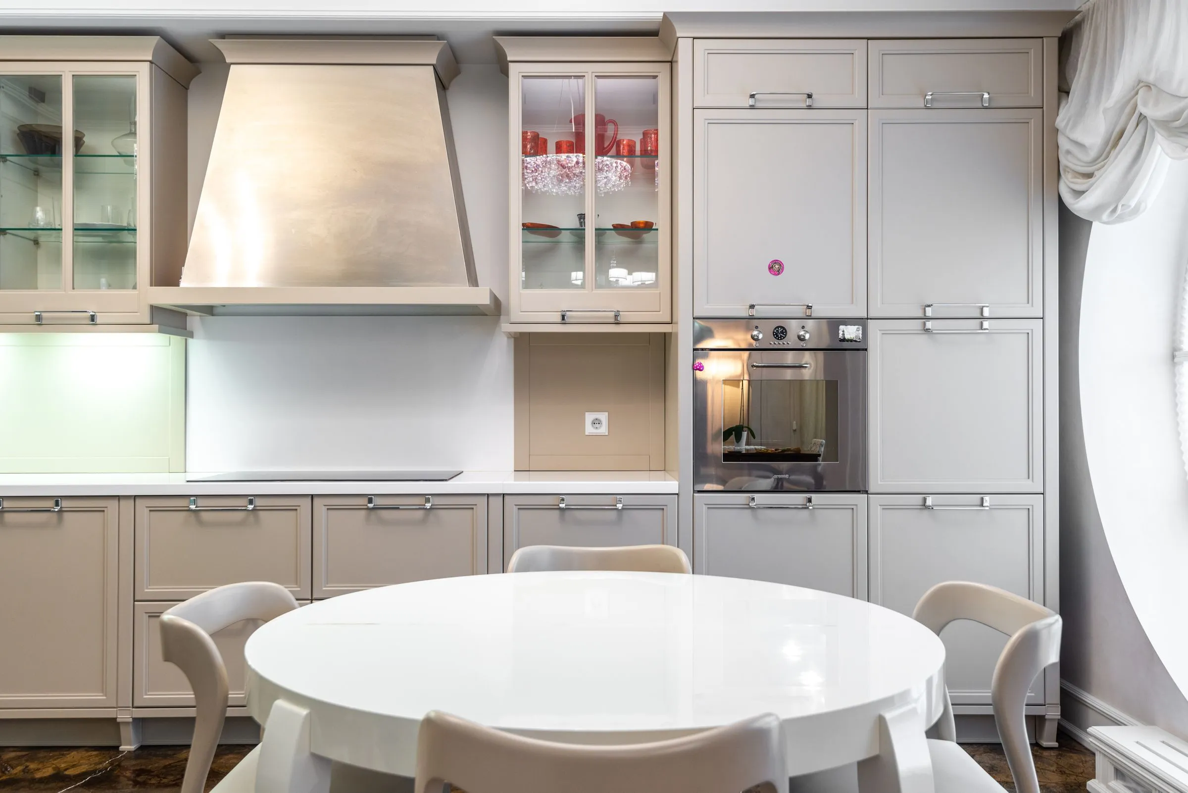 A kitchen with fitted cabinets turning a corner beside a round dining table.