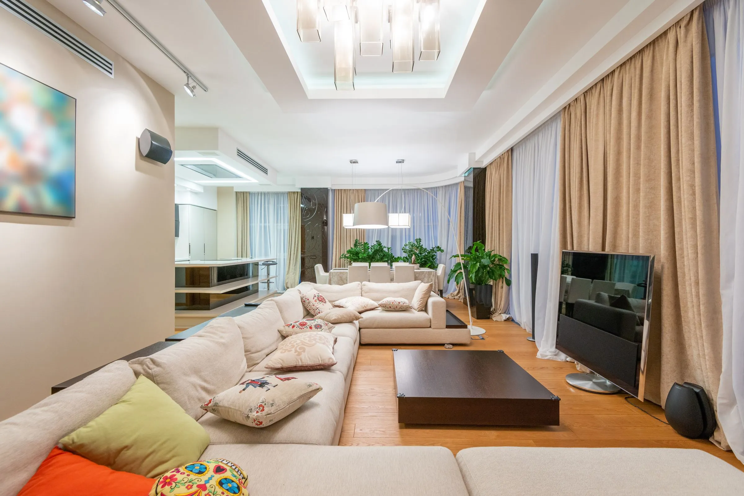 A living room with a comfortable sofa, cushions and a wide window behind.