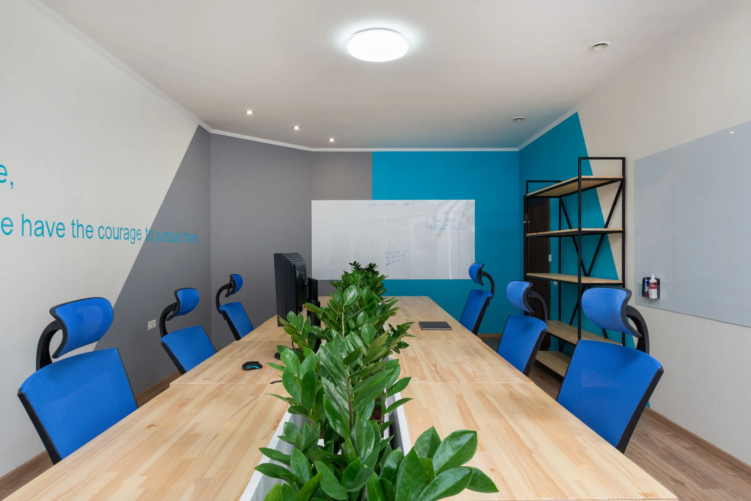 Meeting room at Atelier 27 with a long table, upholstered chairs and planting along the wall.