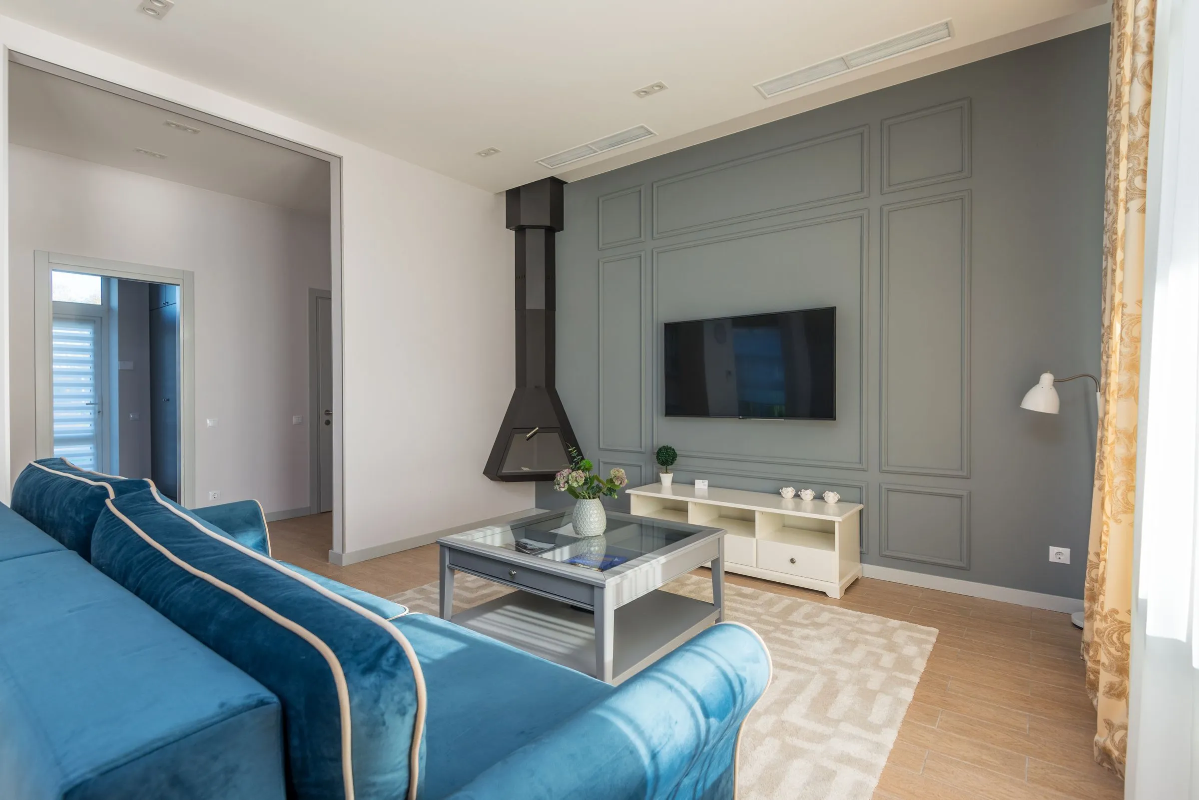 A living room with a deep upholstered sofa facing a wall-mounted screen.