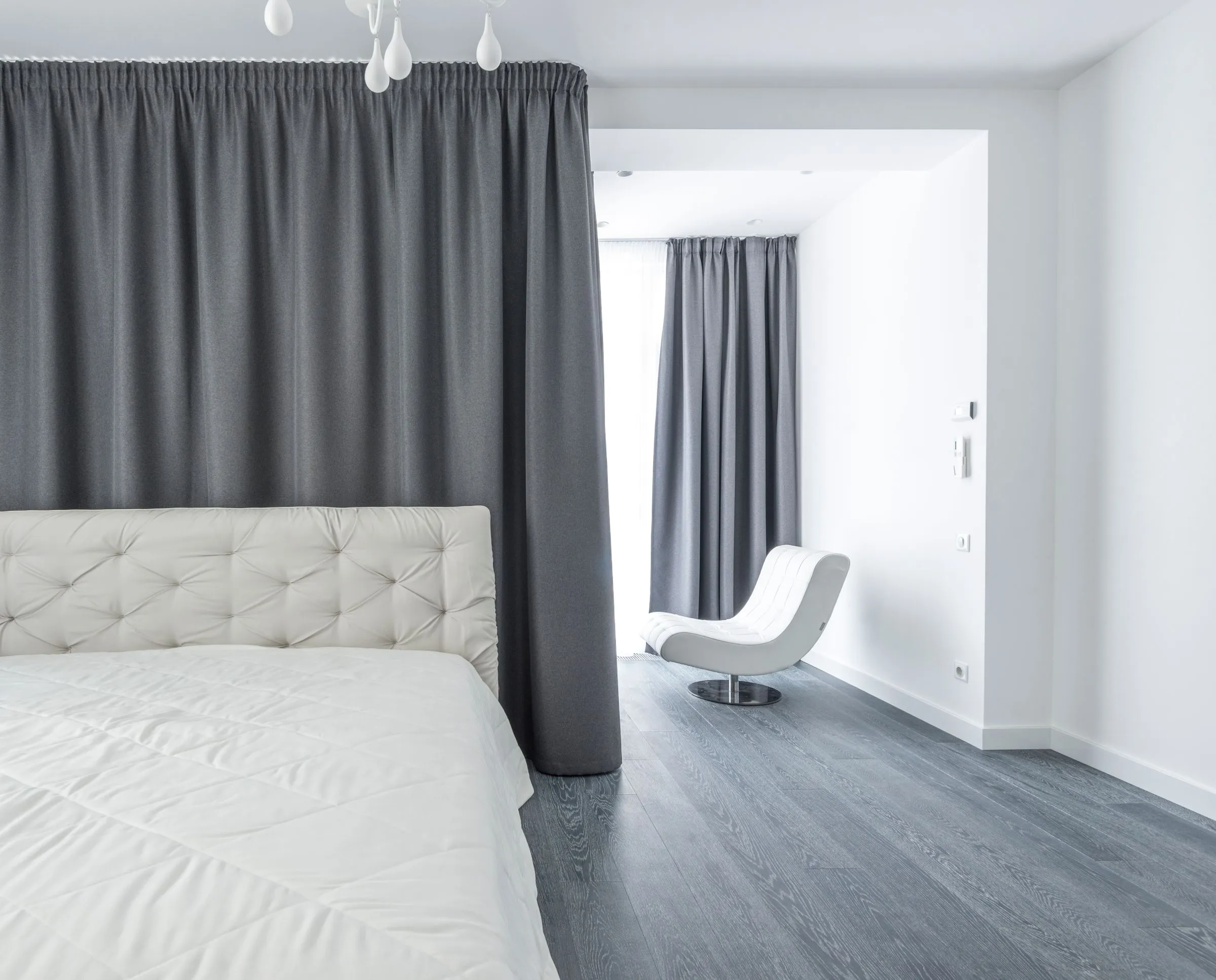 Serein bedroom with white bedding, grey curtains and a low platform bed.