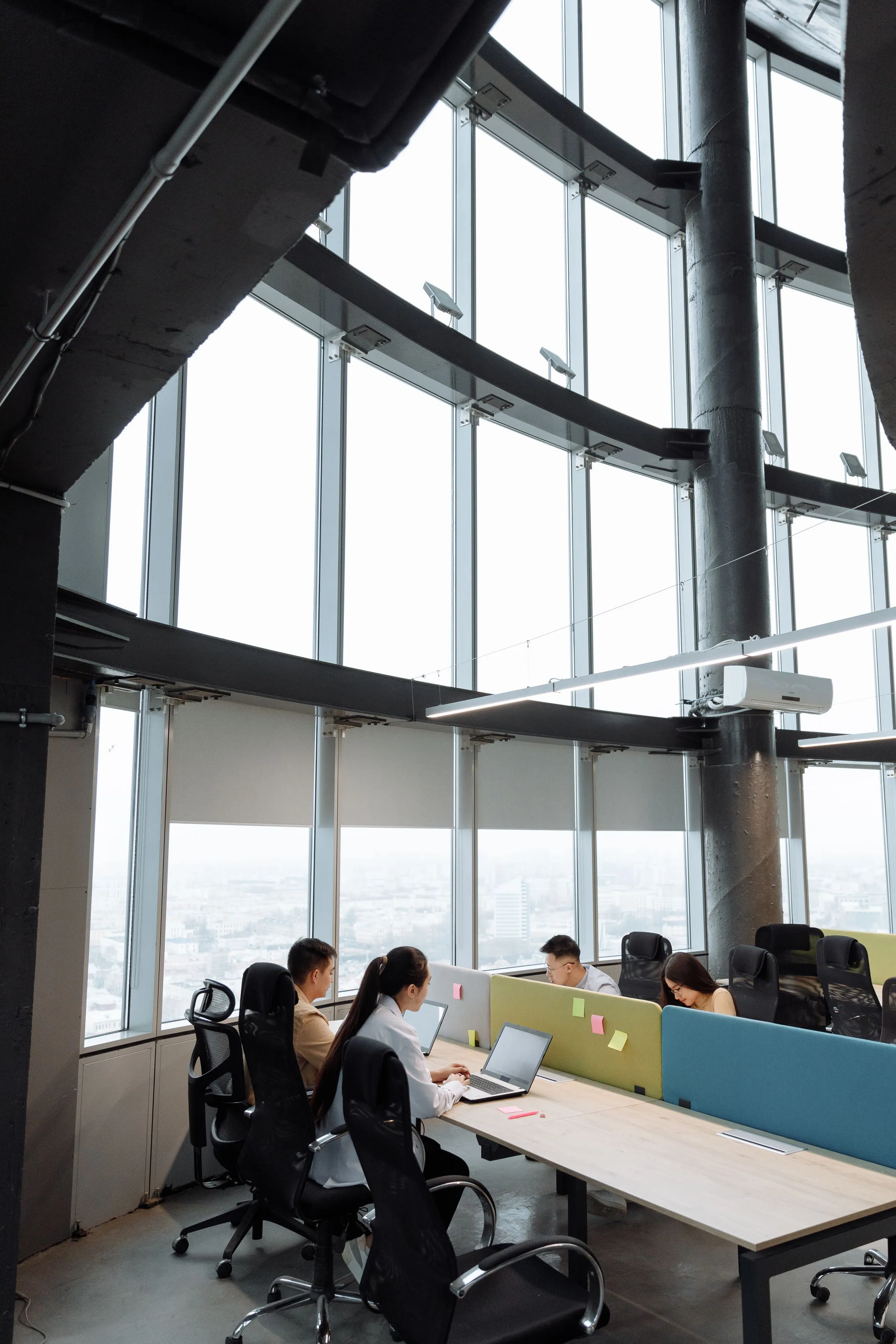An open office floor in a high-rise, with people working at long desks.