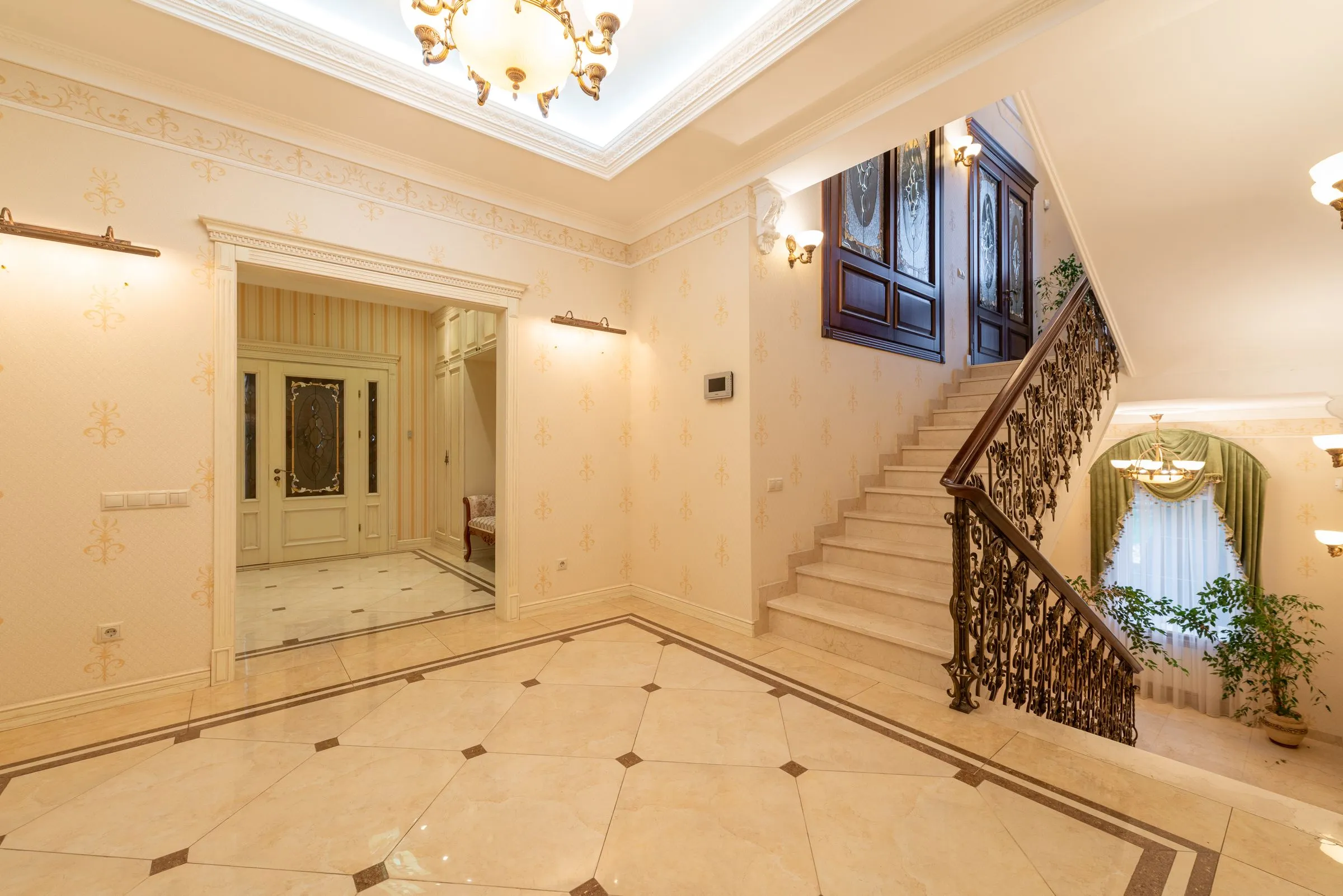 A tall, top-lit hall with a stone staircase and a hanging light fitting.