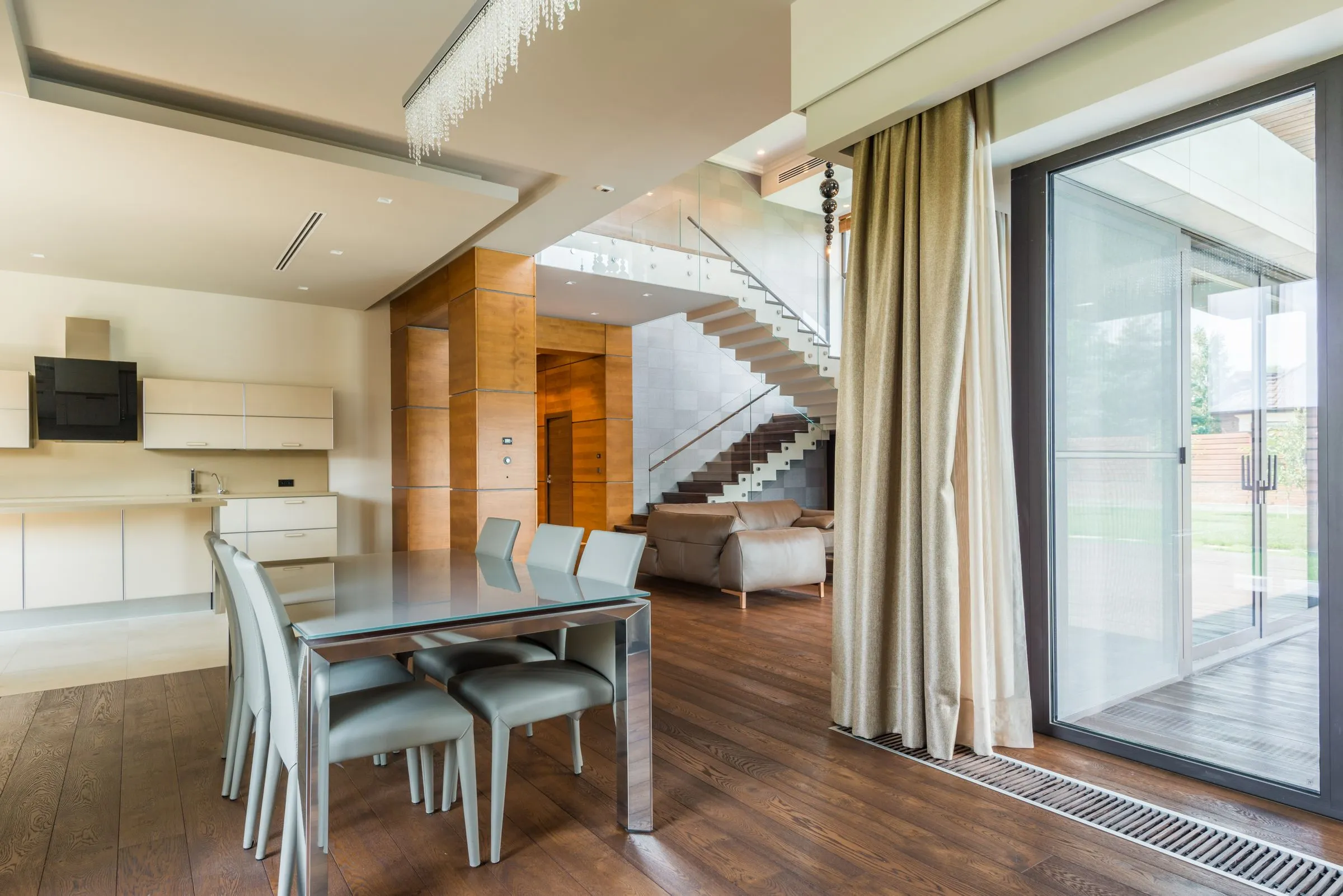 Open-plan living and dining at Casa Terra, with timber floors, a long table and full-height glazing.