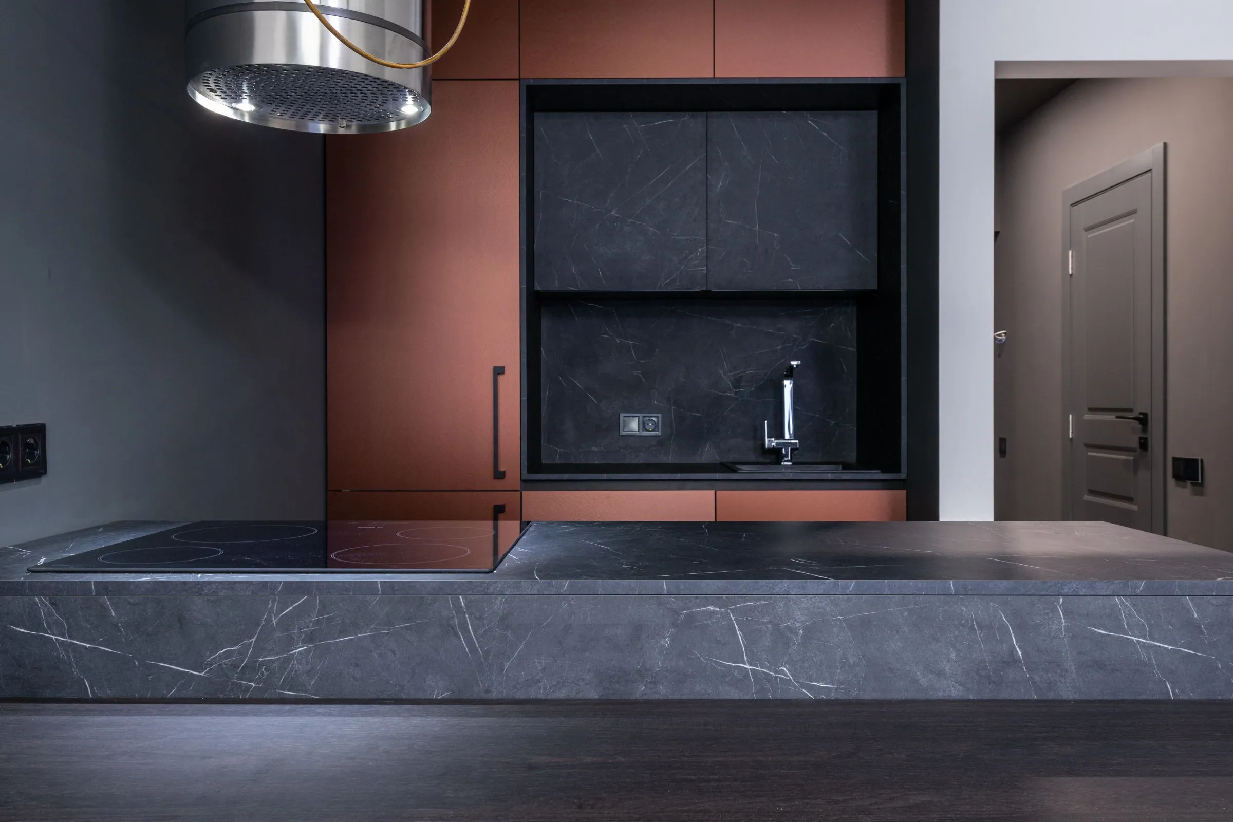 A modern kitchen with marble worktops and sleek handleless fronts.