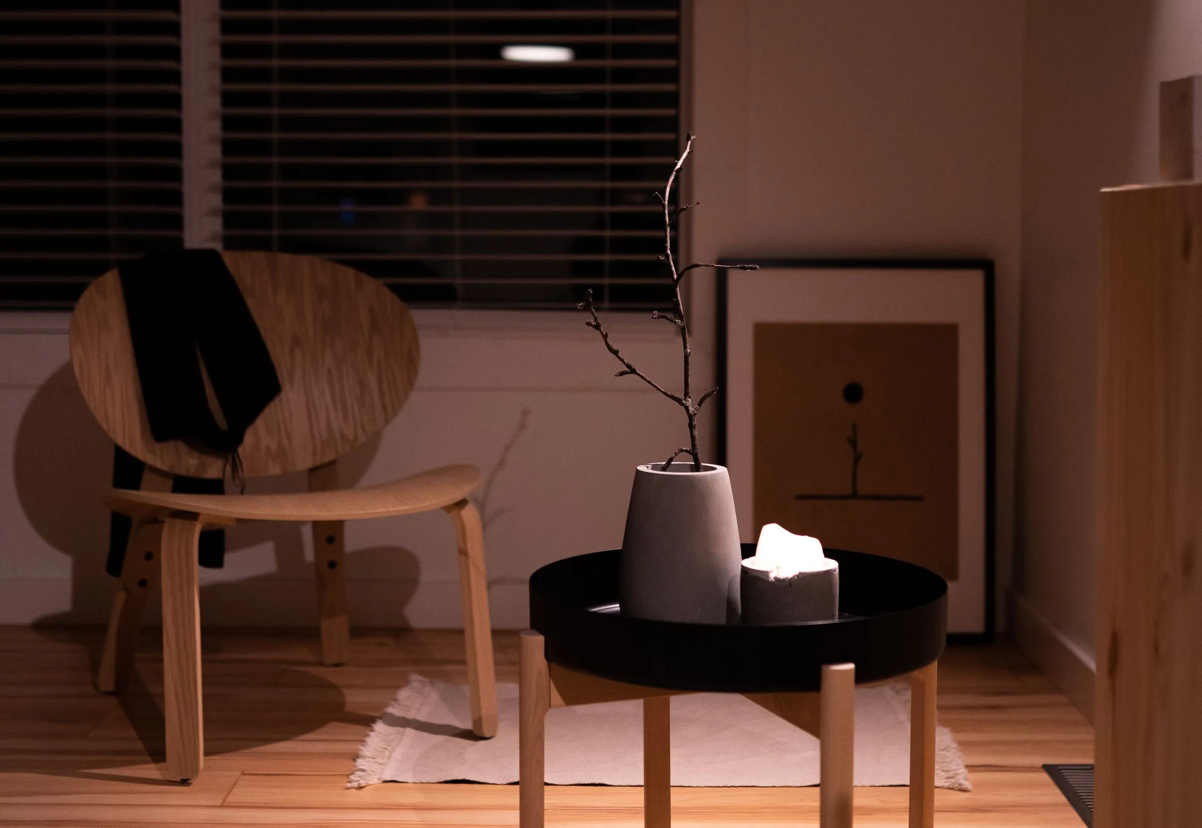 Living room at Maison No. 8, warmly lit against dark walls, with a low chair and a framed picture.