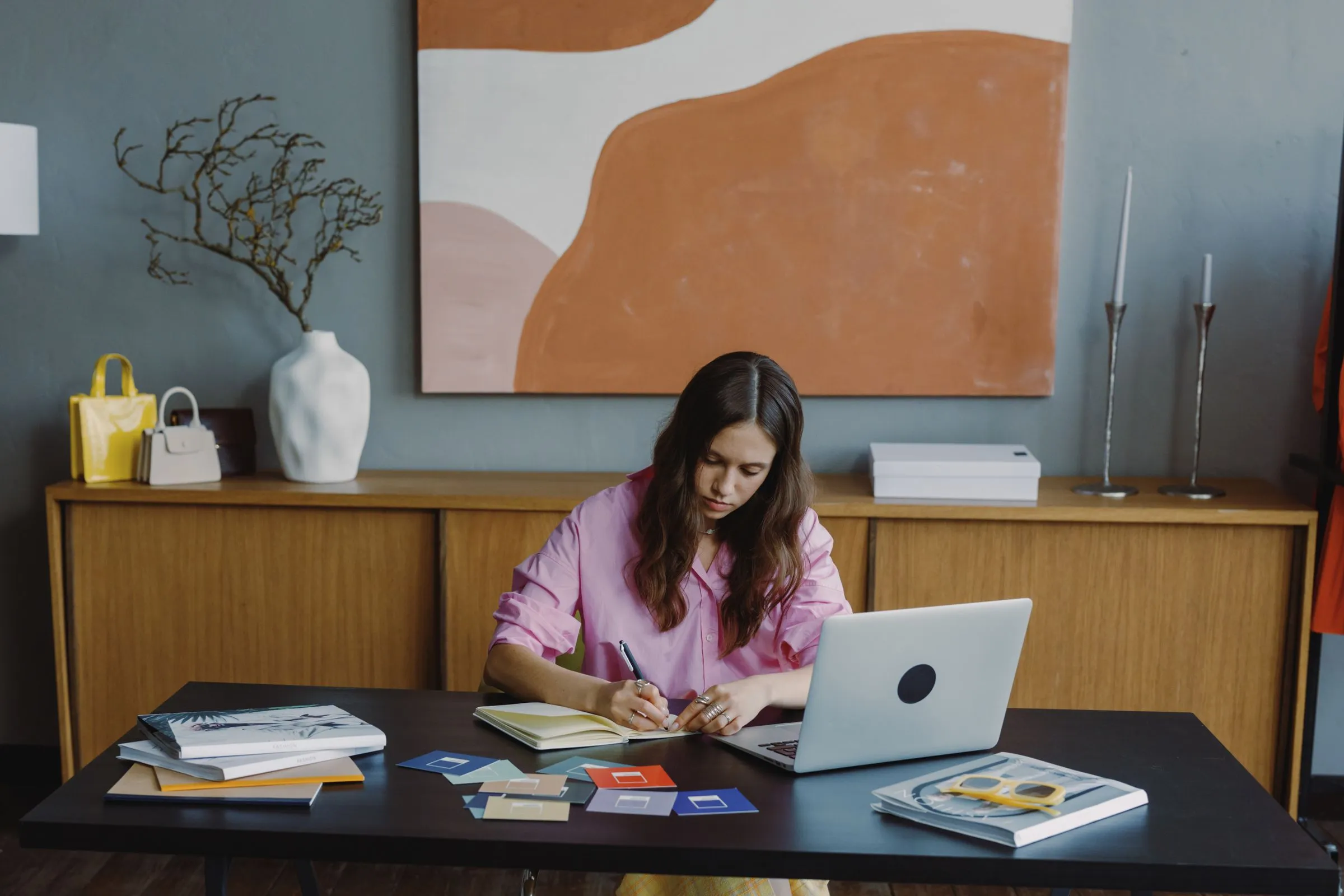 A workspace with a laptop, a notebook and a fan of colour swatches.