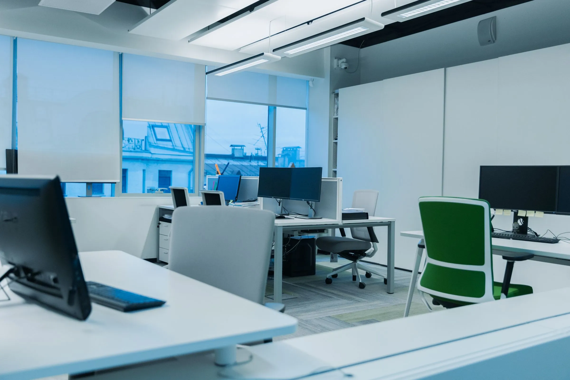 Workstations at Atelier 27 with monitors and daylight from a run of tall windows.