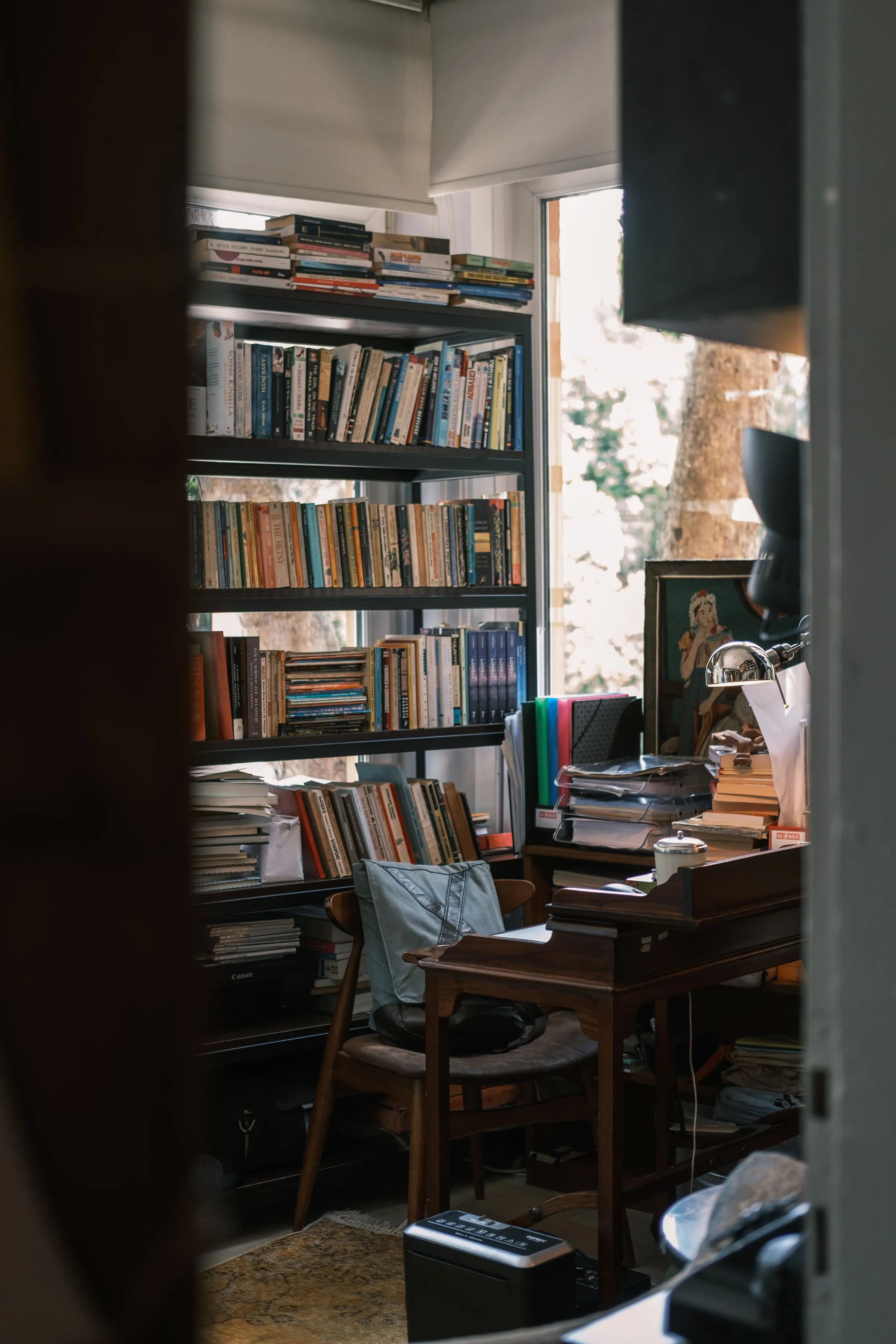 Study at The Reading Room with a filled bookshelf, timber desk and window.