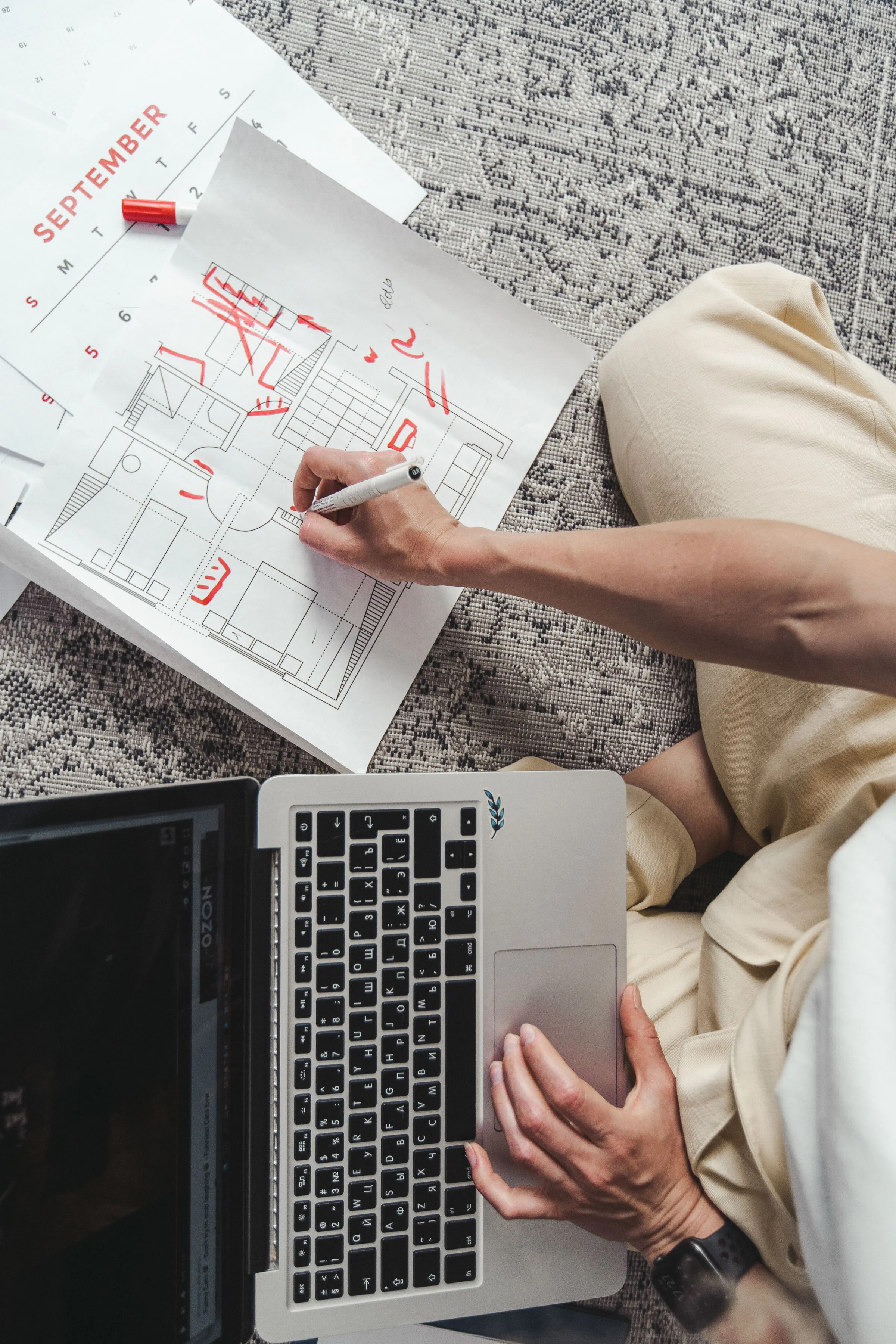 Floor plans being sketched on paper next to an open laptop.