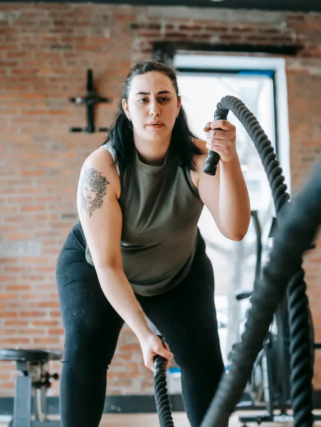 Coach working battle ropes in front of an exposed brick wall