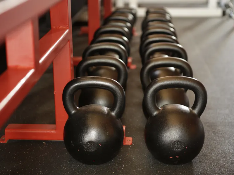Cast-iron kettlebells lined up on a painted rack