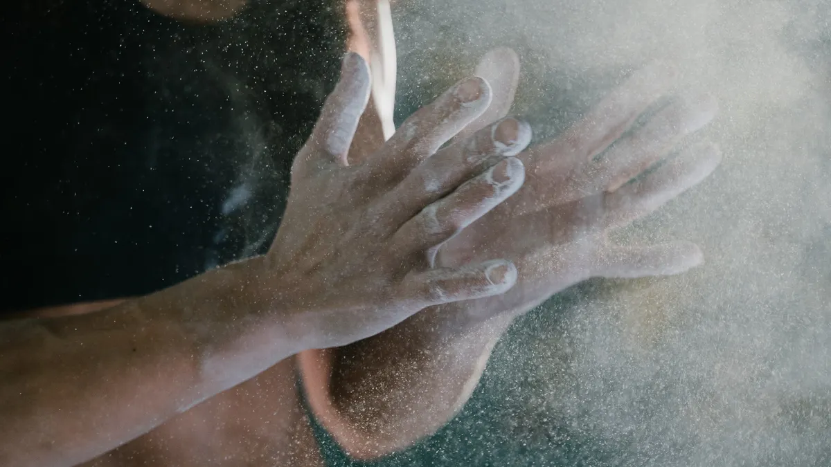 Athlete clapping chalk from their hands before a heavy set