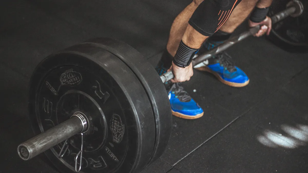 Barbell being pulled from the floor, shot low and close