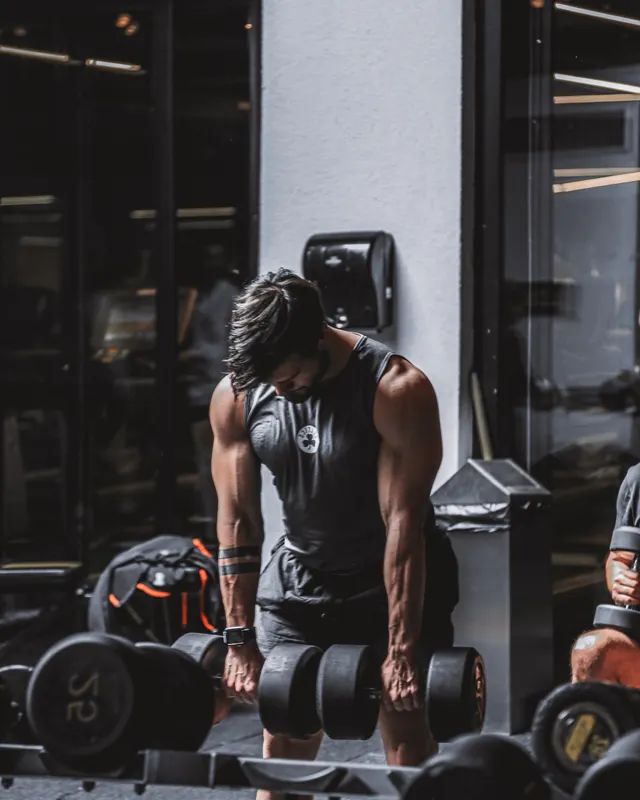Athlete rowing a heavy dumbbell in a dark training room