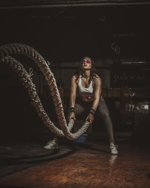 Athlete driving battle ropes under a single overhead light